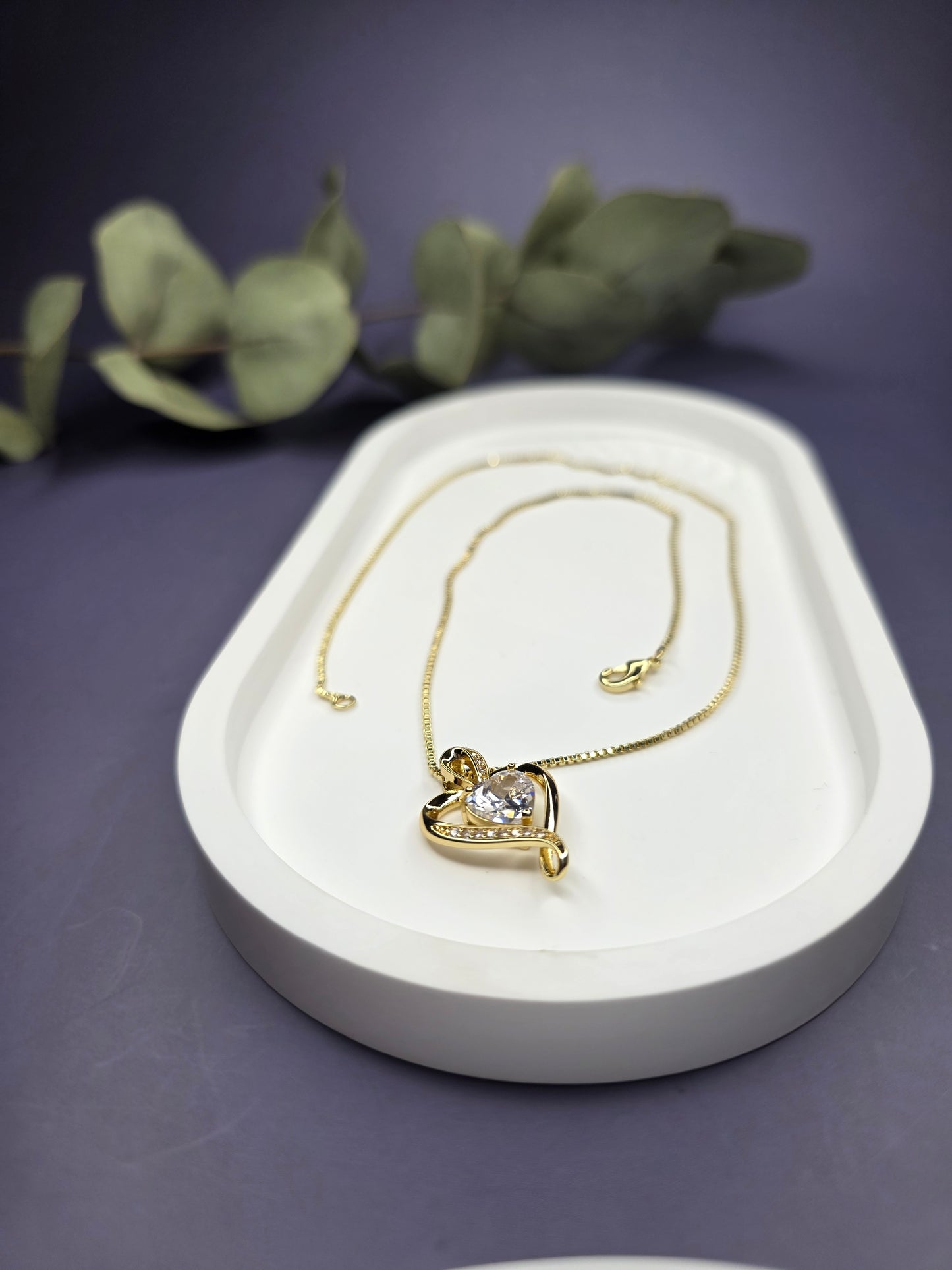 Eternal Heart Solitaire gold necklace resting on a white oval jewelry tray. This elegant 18K gold-plated heart pendant is designed for effortless style and profound meaning - My Silver Lining.