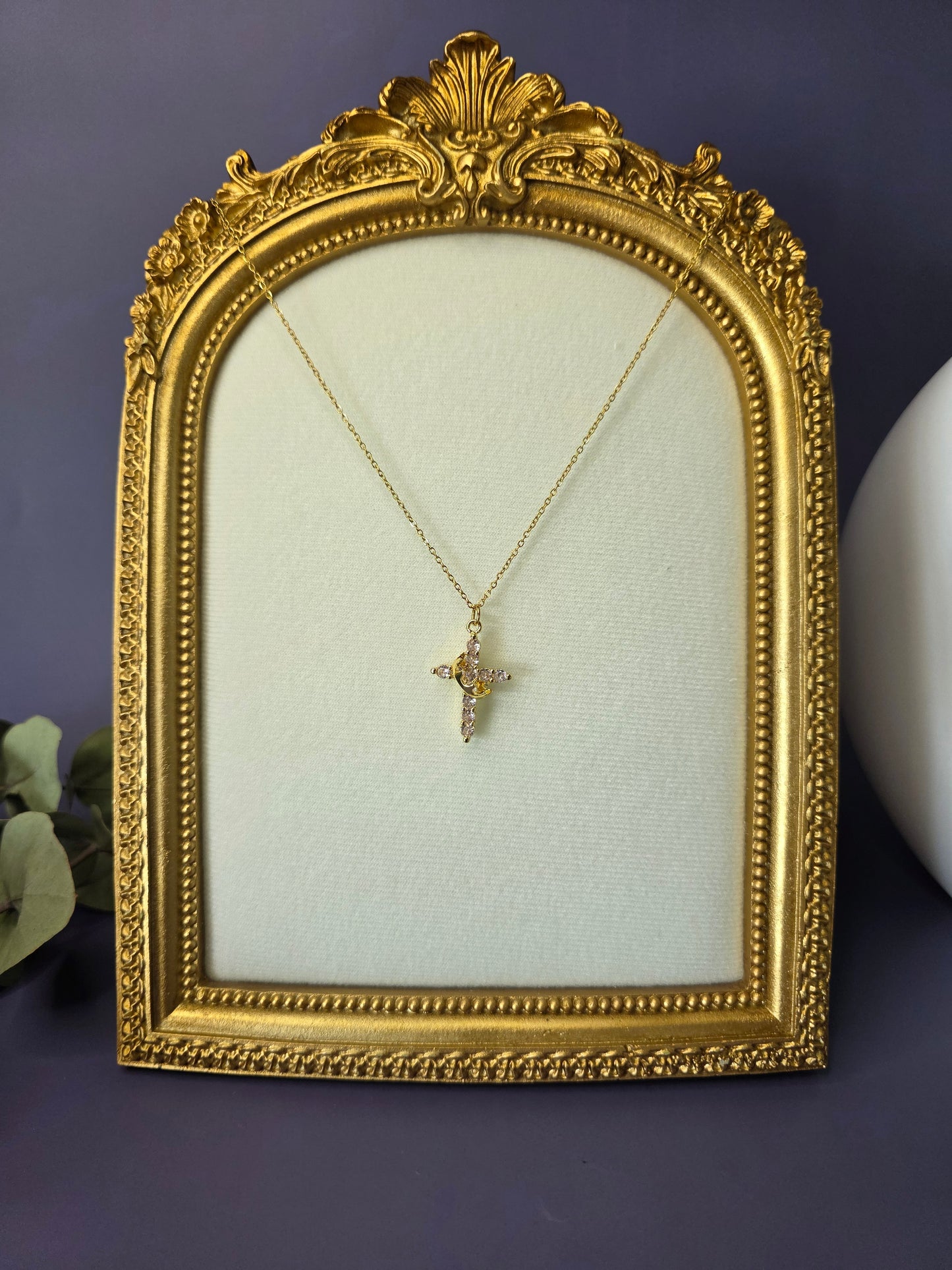 Glimmering Gold Grace necklace displayed elegantly on a gold frame. This 18K gold plated waterproof cross necklace features premium pave cubic zirconia stones — My Silver Lining.