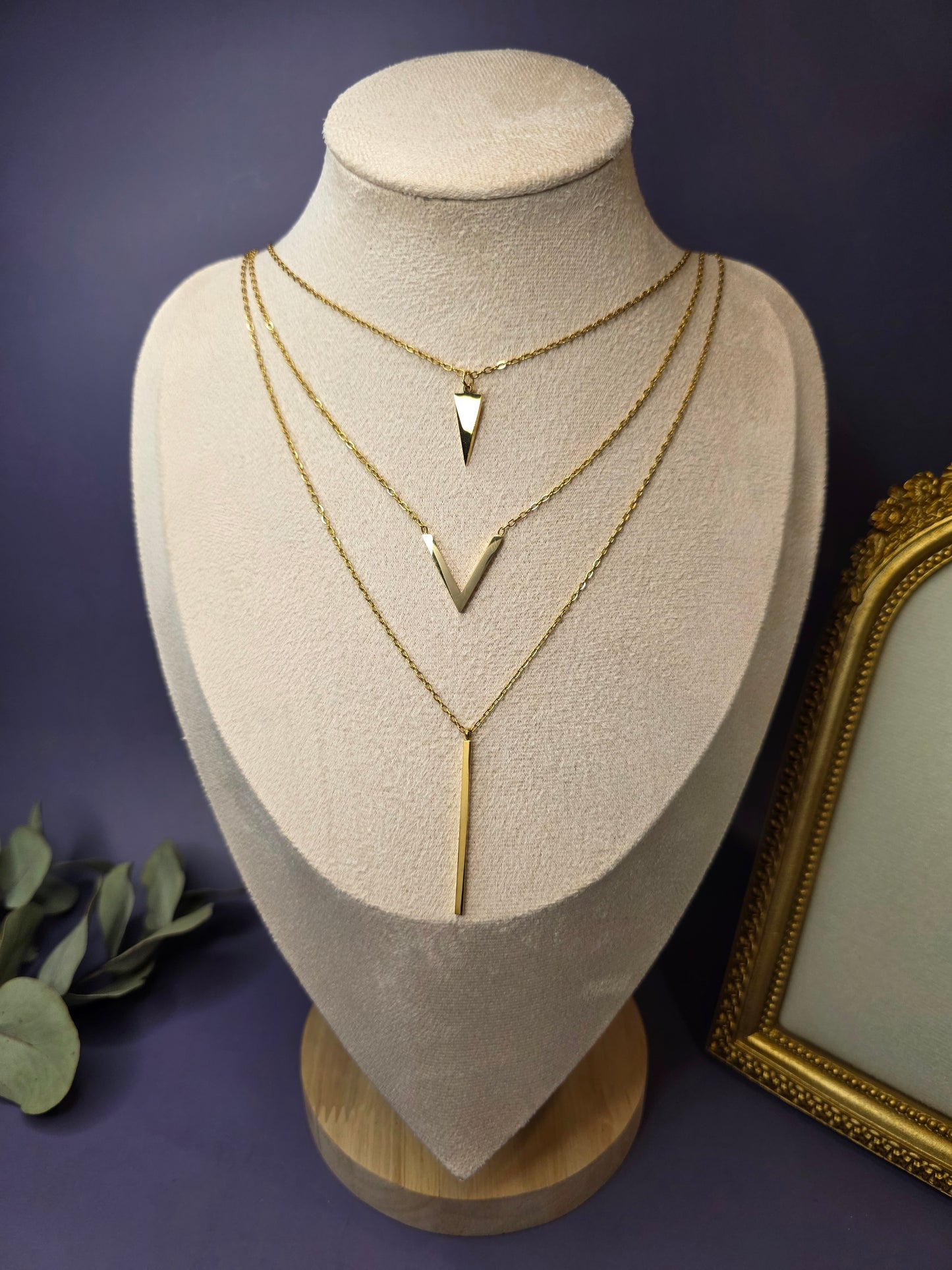 Golden Flying V layered necklace styled on a white jewelry bust. This 18K gold plated waterproof necklace features a triangle, chevron, and bar pendant - My Silver Lining.