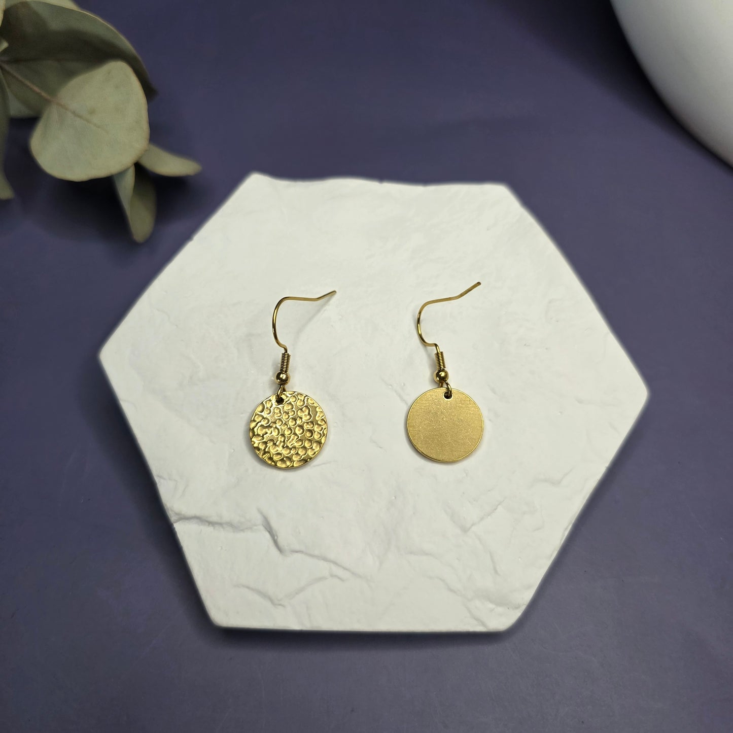 Top view of the Honey Gold Hammered Drops on a white stone, showing the textured 316 stainless steel finish — My Silver Lining.