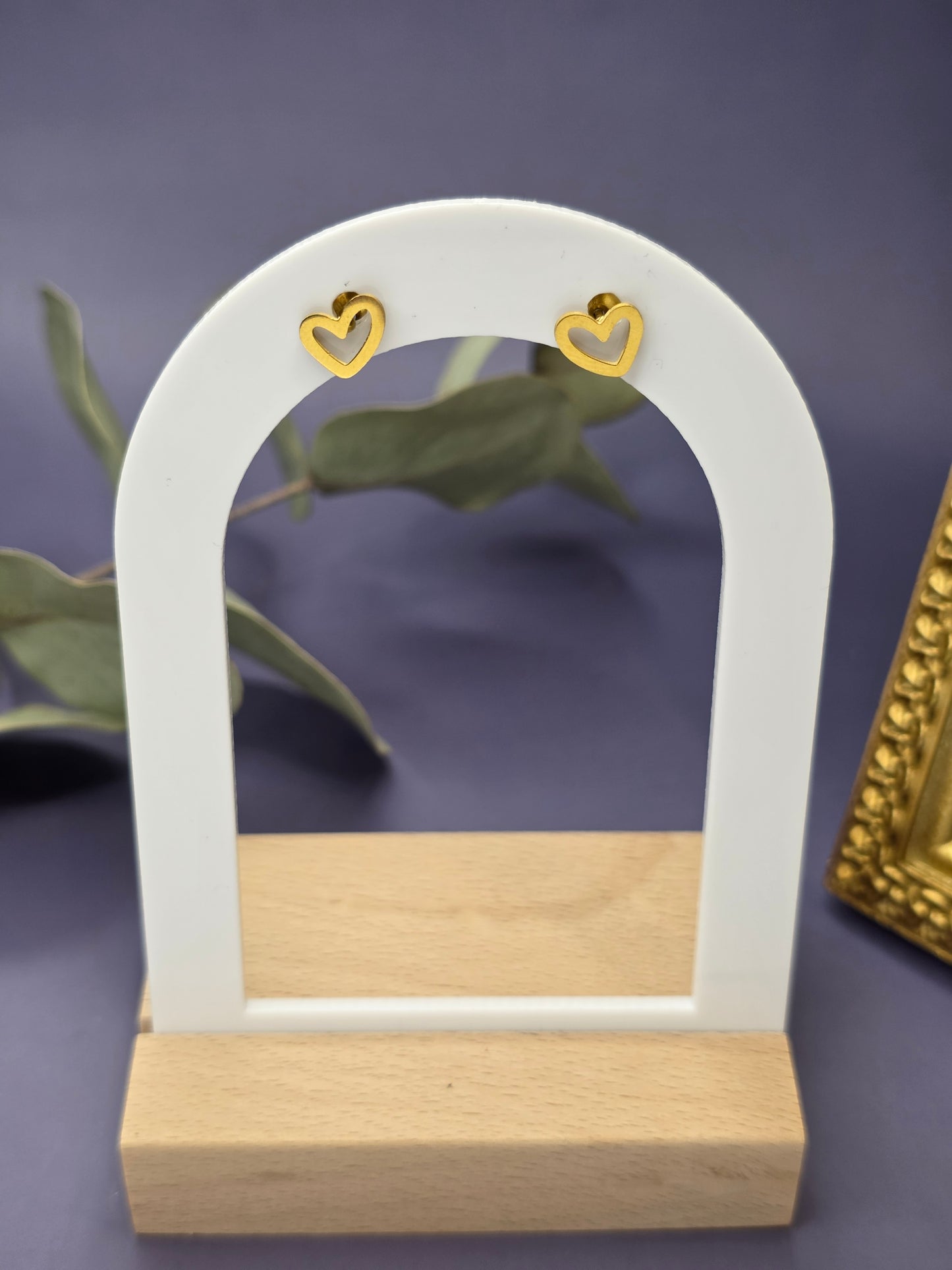 Little Cupido golden heart stud earrings displayed on a white arch stand. These waterproof KC gold-plated stainless steel studs are hypoallergenic and tarnish-resistant - My Silver Lining.