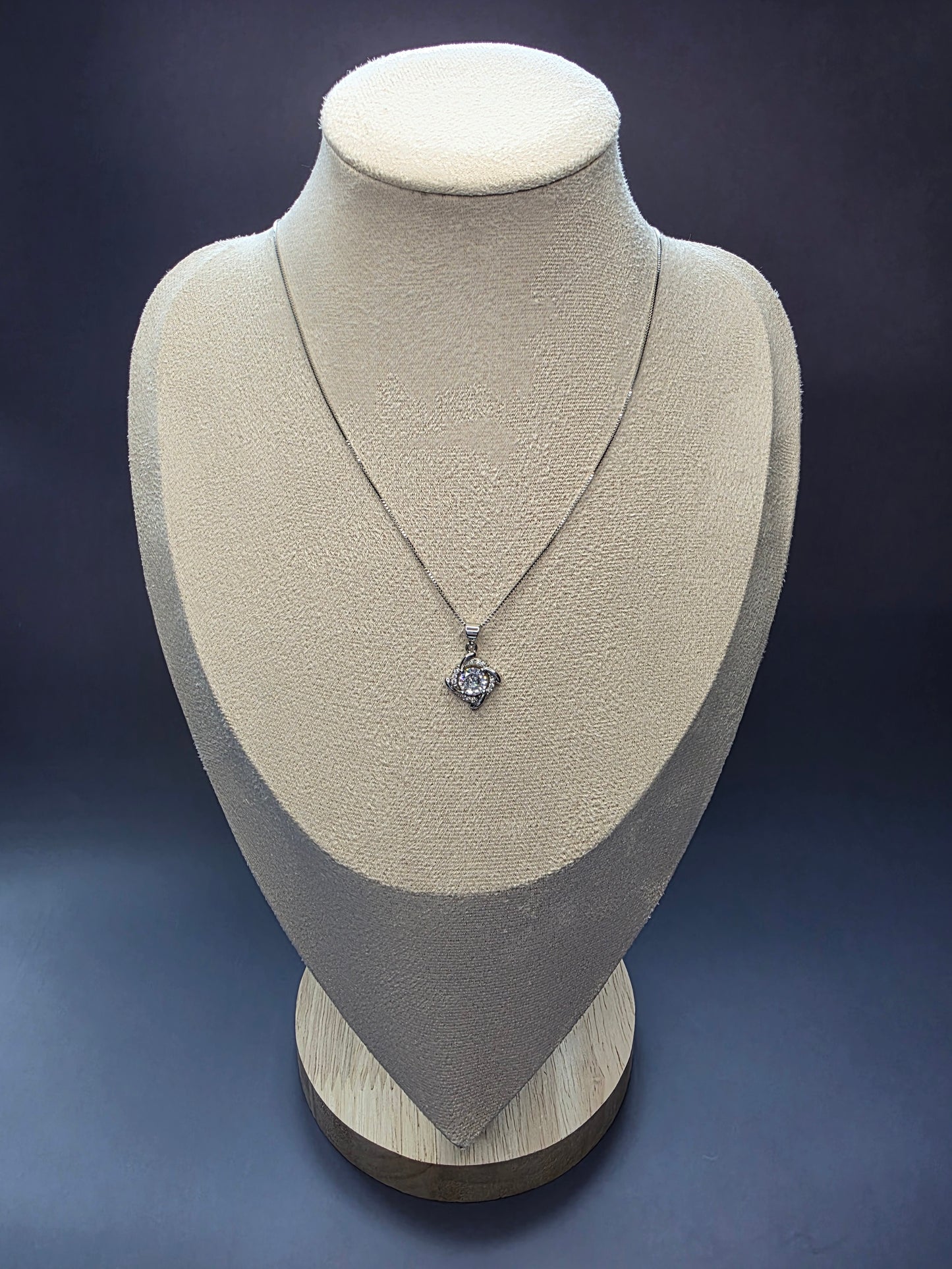 Elegant sterling silver necklace with a brilliant round cubic zirconia stone set in a polished silver swirl or halo pendant design.