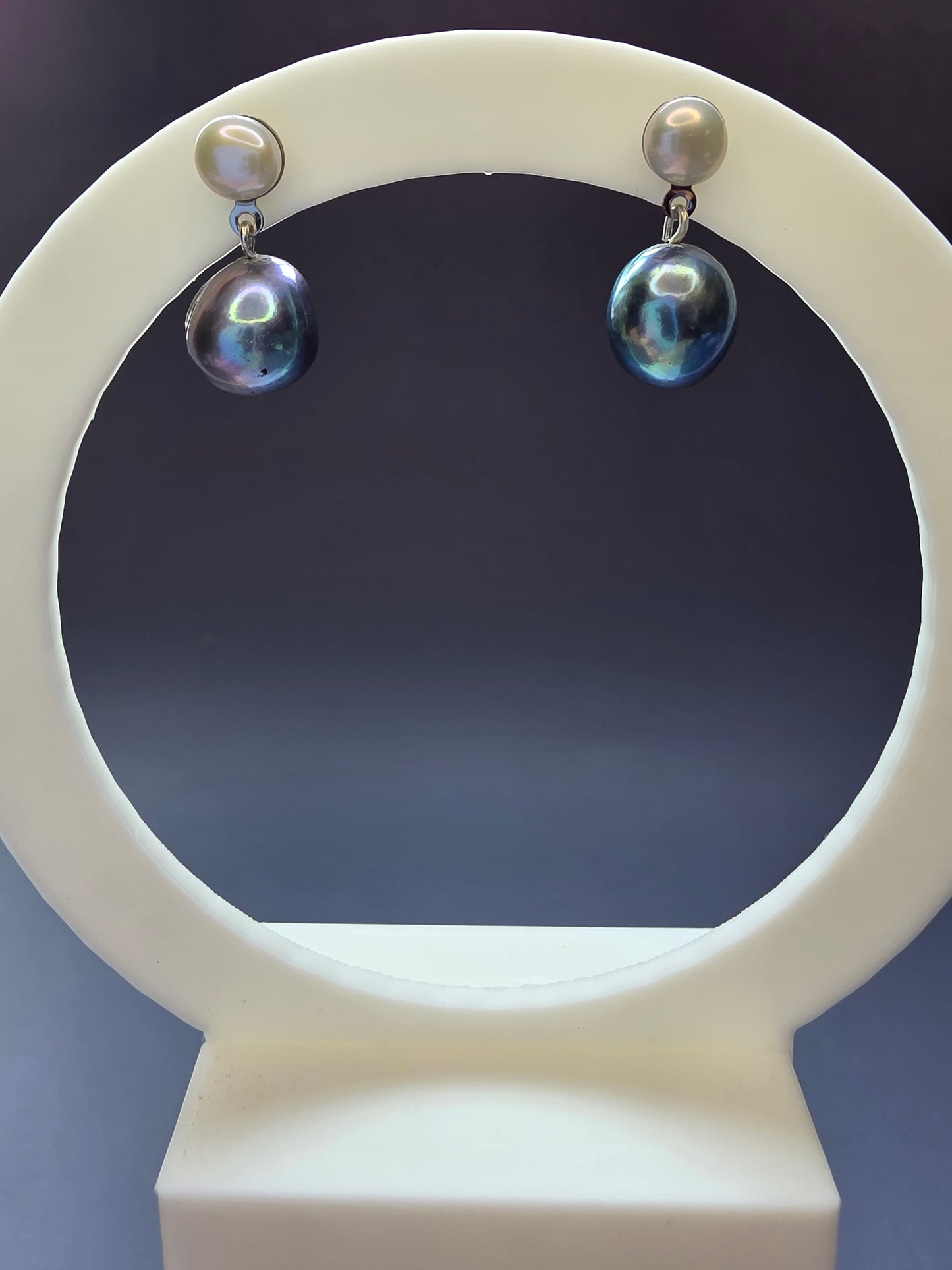 Black Moon Drops featured on a white arch jewelry stand. These unique black iridescent pearl drop earrings provide a sophisticated contrast and hypoallergenic finish - My Silver Lining.