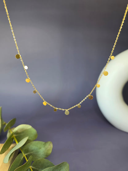 Delicate gold-toned necklace featuring multiple small, flat, dangling disc or coin pendants evenly spaced along the chain, perfect for layering.