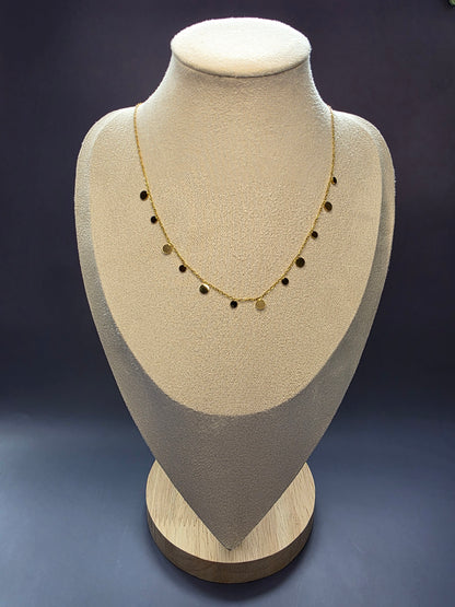 Delicate gold-toned necklace featuring multiple small, flat, dangling disc or coin pendants evenly spaced along the chain, perfect for layering.