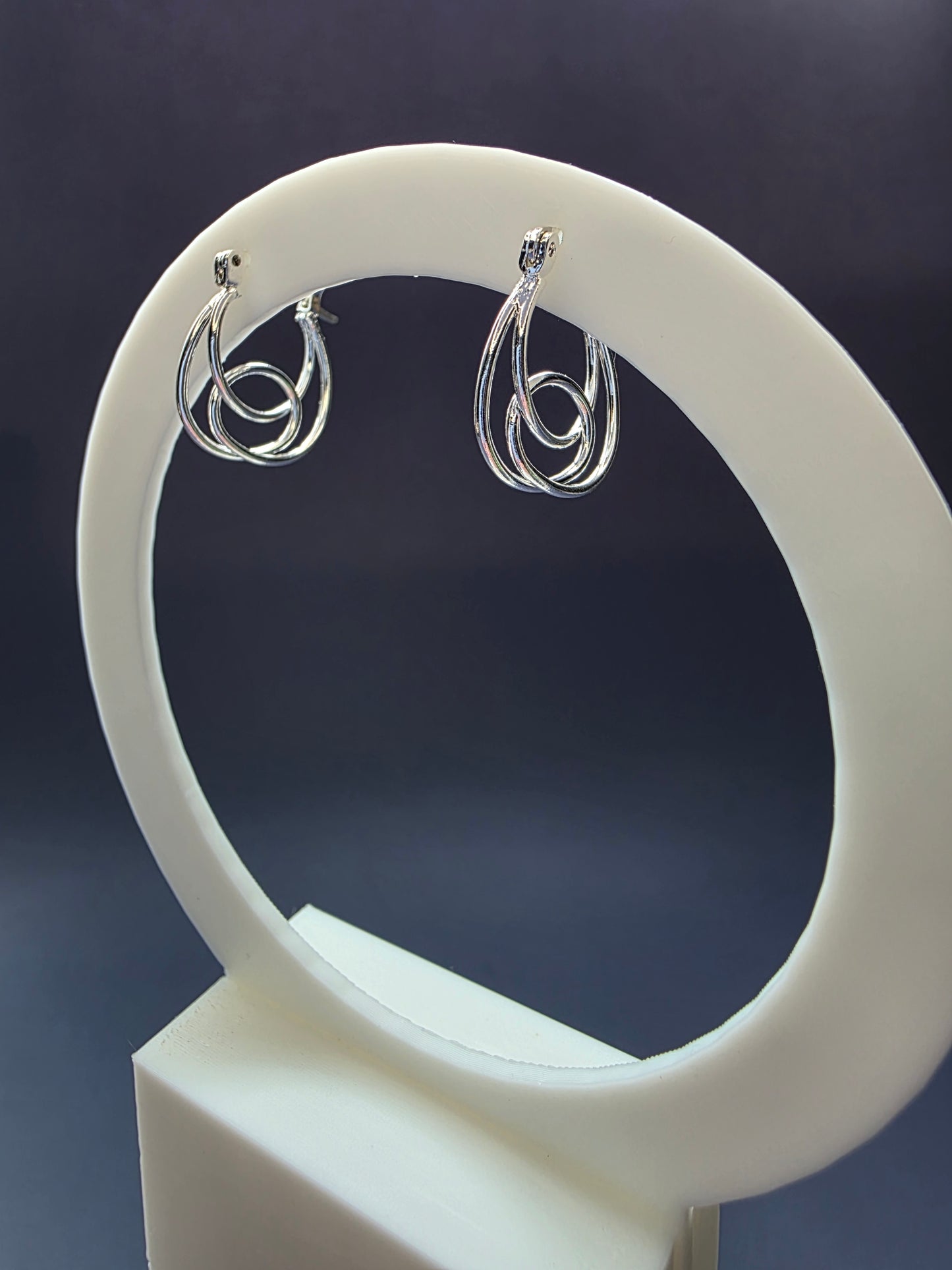 Eternal Embrace hoops featured on a white arch jewelry stand. These genuine S925 sterling silver earrings provide a modern interlocking silhouette and hypoallergenic finish - My Silver Lining.