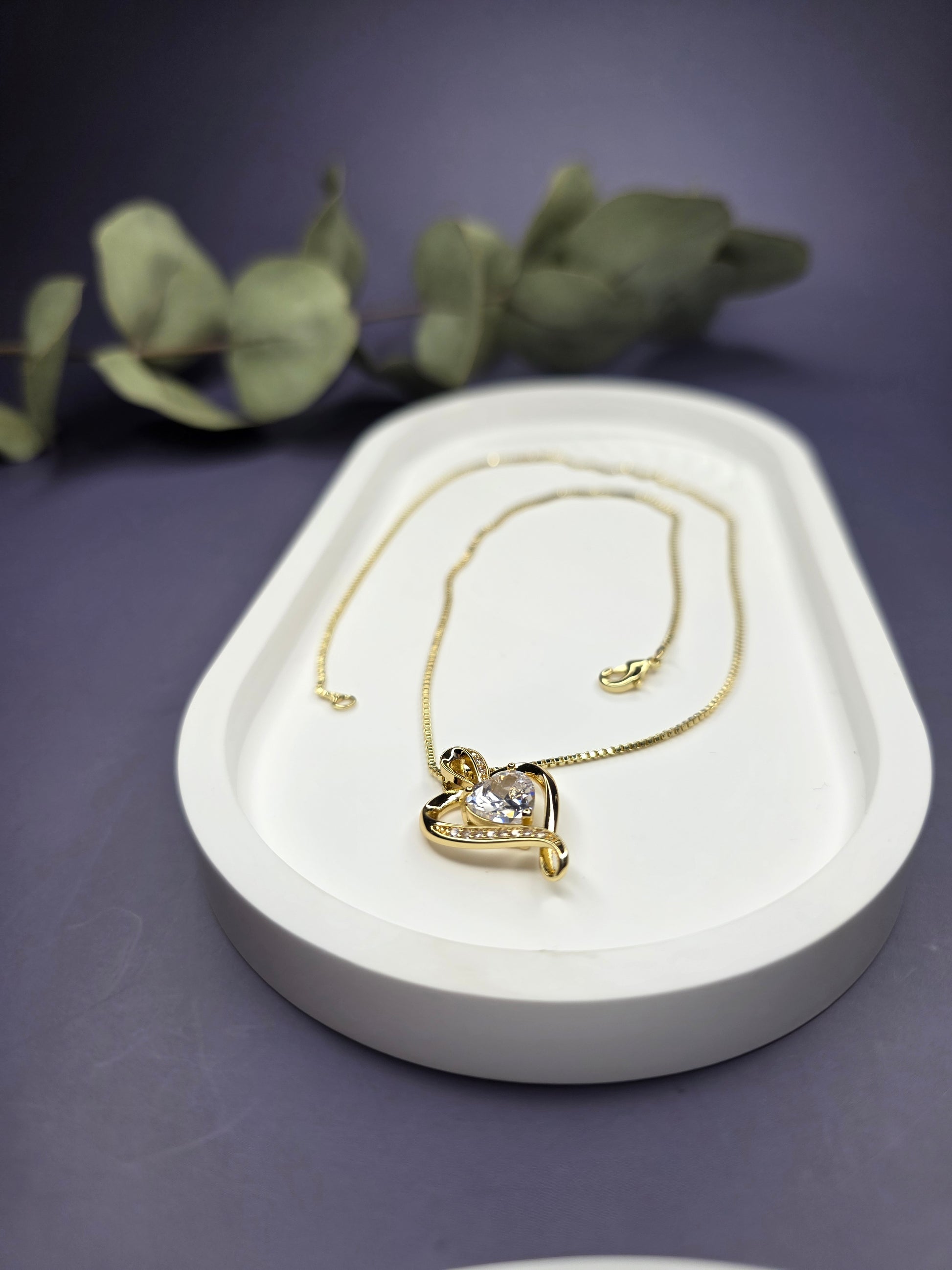 Eternal Heart Solitaire gold necklace resting on a white oval jewelry tray. This elegant 18K gold-plated heart pendant is designed for effortless style and profound meaning - My Silver Lining.