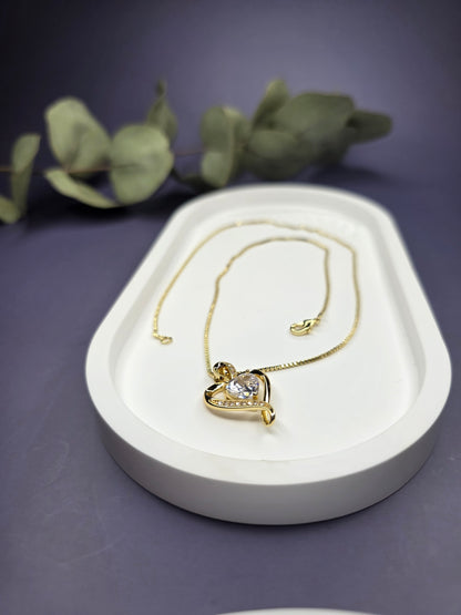 Eternal Heart Solitaire gold necklace resting on a white oval jewelry tray. This elegant 18K gold-plated heart pendant is designed for effortless style and profound meaning - My Silver Lining.