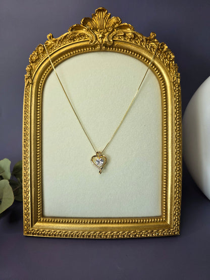 The Eternal Heart Solitaire necklace displayed in a vintage gold frame. A timeless 18K gold heart pendant symbolizing enduring love and commitment with a graceful sparkle - My Silver Lining.