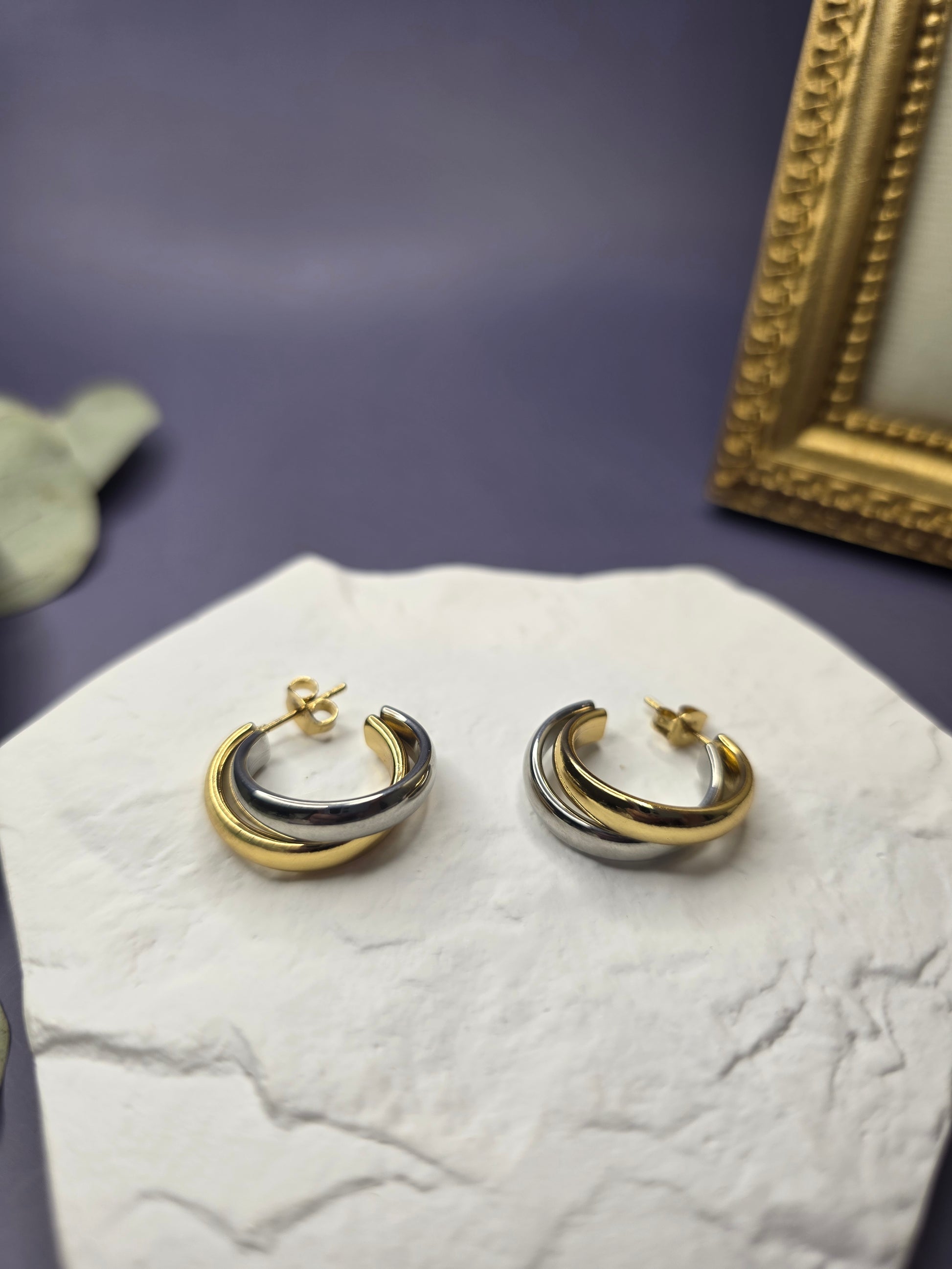 Detail shot of Gemini Half Hoops resting on a white textured stone. Crafted from high-quality waterproof stainless steel, these two-tone chunky earrings represent perfect balance and modern sophistication - My Silver Lining.