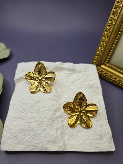 Front view of Sunburst Blossom gold flower stud earrings on a white display stand. Bold 18K gold-toned tarnish-resistant floral earrings for a modern statement look - My Silver Lining.