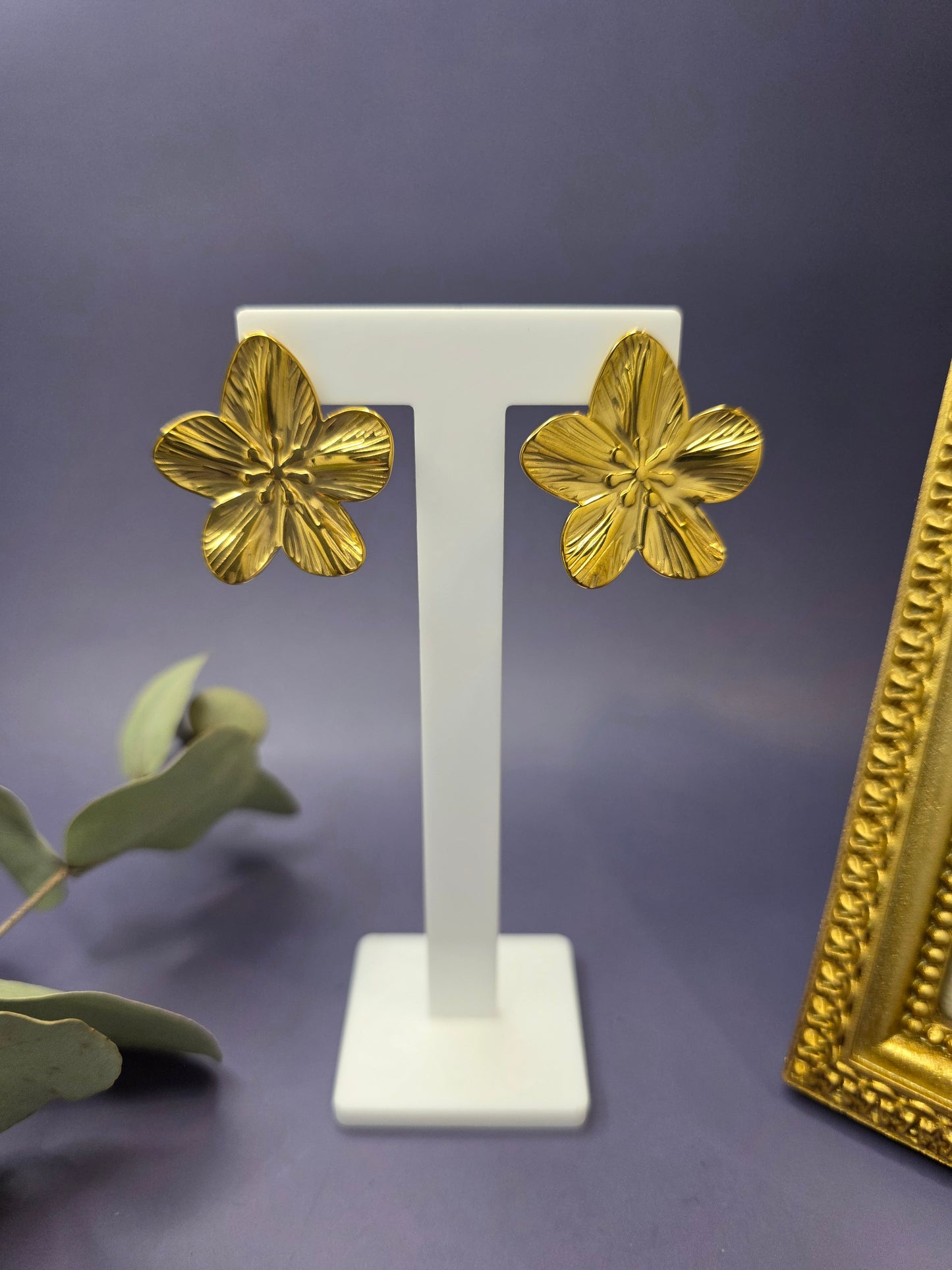 Flatlay of Sunburst Blossom gold flower stud earrings. These waterproof and hypoallergenic 304 stainless steel earrings feature a unique sunburst textured finish - My Silver Lining.