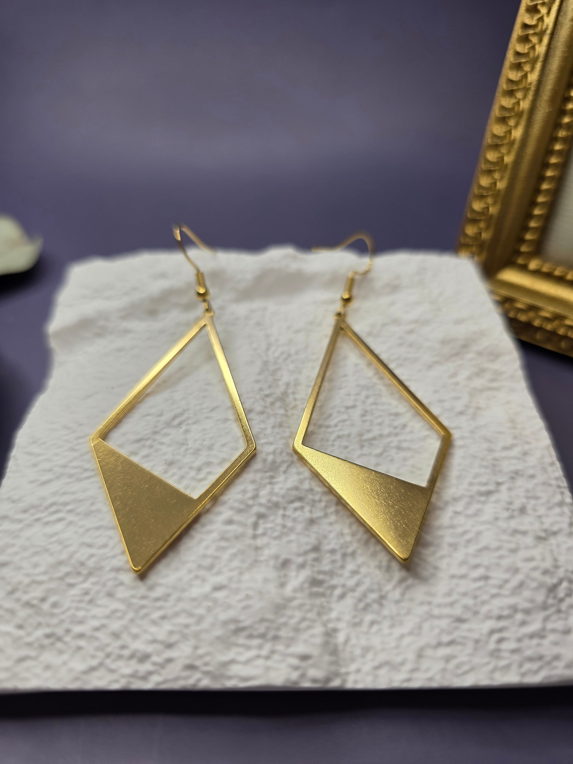 Detail shot of Golden Anchor Drops resting on a white textured stone. High-quality waterproof and tarnish-resistant gold earrings with hypoallergenic medical-grade needles for sensitive ears - My Silver Lining.