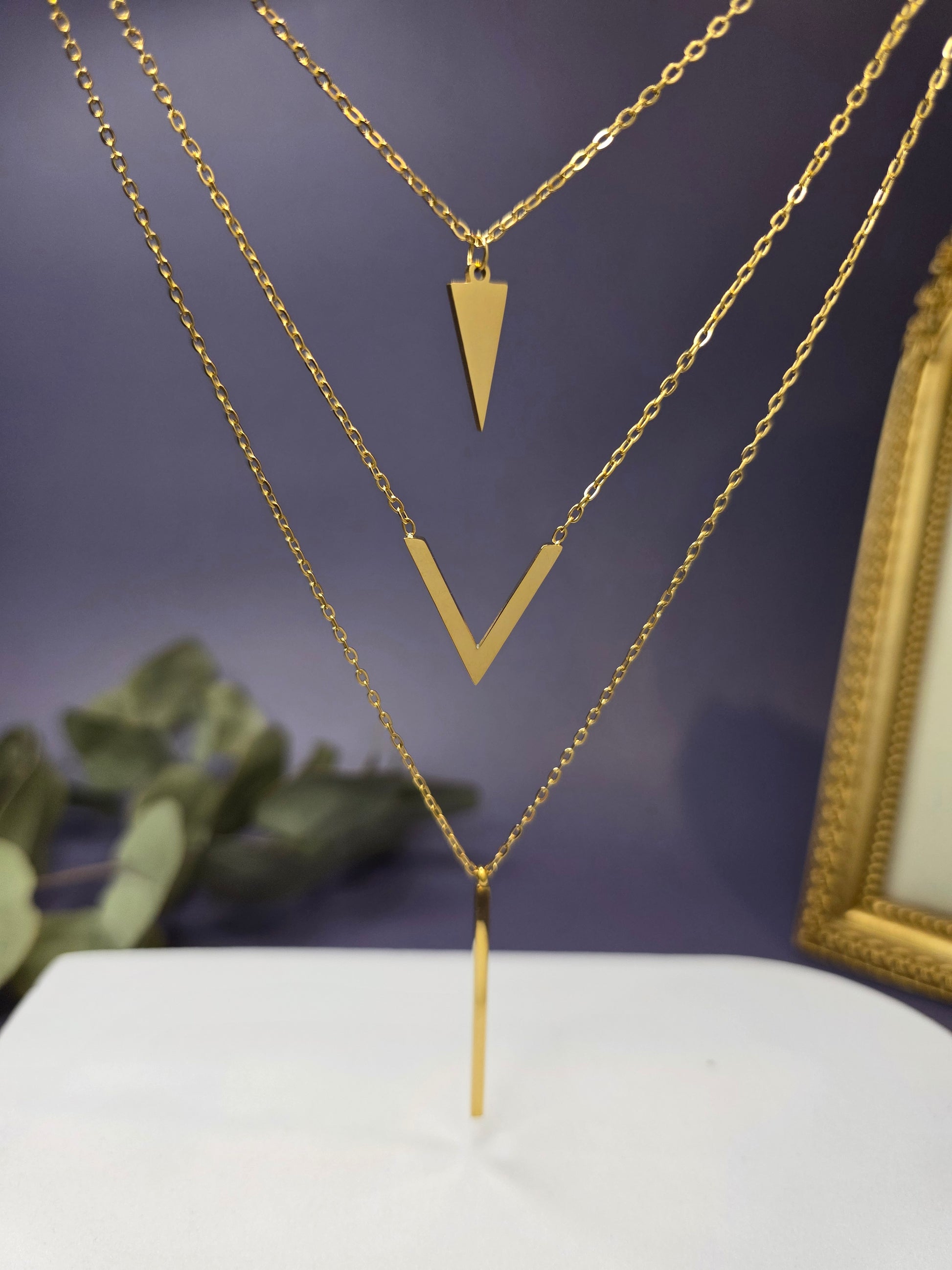 Golden Flying V necklace shown floating to highlight the three-layer geometric design. Tarnish-resistant 18K gold plated stainless steel with a single clasp - My Silver Lining.