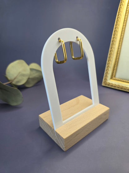 Golden frame hoops featured on a white arch jewelry stand. These 316L stainless steel waterproof sleeper earrings provide a sleek rectangular silhouette and a hypoallergenic finish for comfortable wear - My Silver Lining.