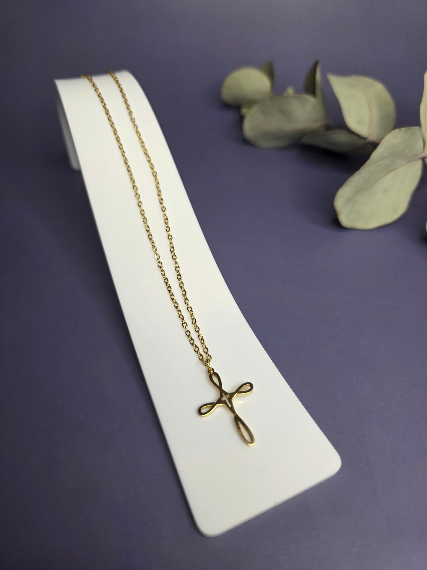 Angled view of the Golden Infinity Cross Necklace on a white display stand — My Silver Lining.
