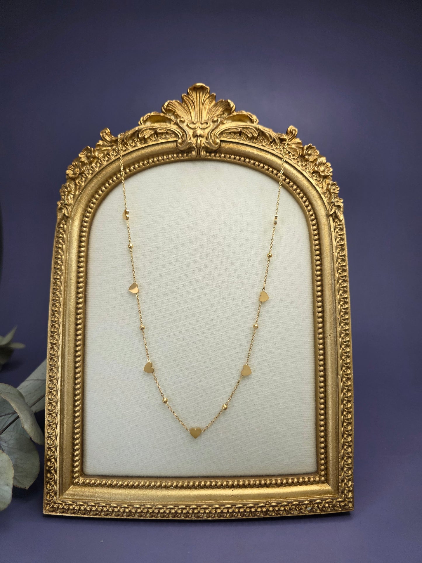 Golden Rhythm Heart necklace styled on a golden frame. This 18K gold plated station necklace features multiple polished heart charms in waterproof stainless steel - My Silver Lining.