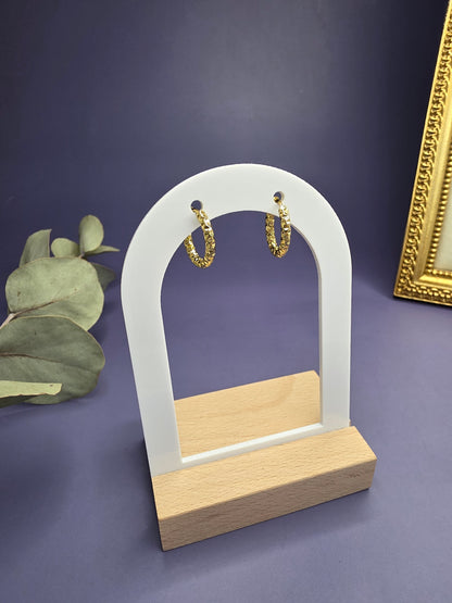 Golden ripple huggies featured on a white arch jewelry stand. These 304 stainless steel waterproof sleeper earrings with KC gold plating provide a sleek, textured silhouette and a hypoallergenic finish for comfortable wear - My Silver Lining.