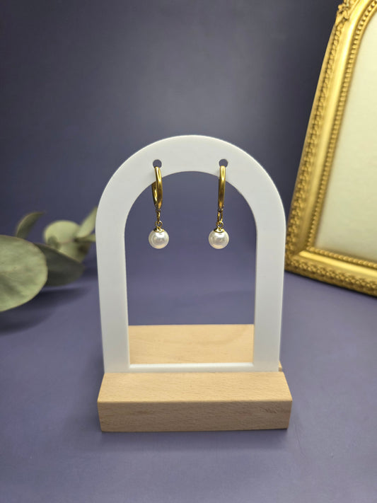 Golden shores pearl earrings featured on a white arch jewelry stand. These 18k gold plated waterproof hoops with imitation pearl drops offer a sophisticated and tarnish-resistant accessory for every day wear - My Silver Lining.