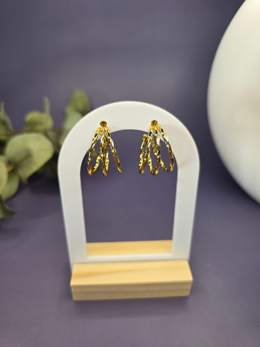 Golden Twist hoops featured on a white arch jewelry stand. These tarnish-resistant 304 stainless steel hoops provide a bold textured silhouette and hypoallergenic finish for comfortable wear - My Silver Lining..