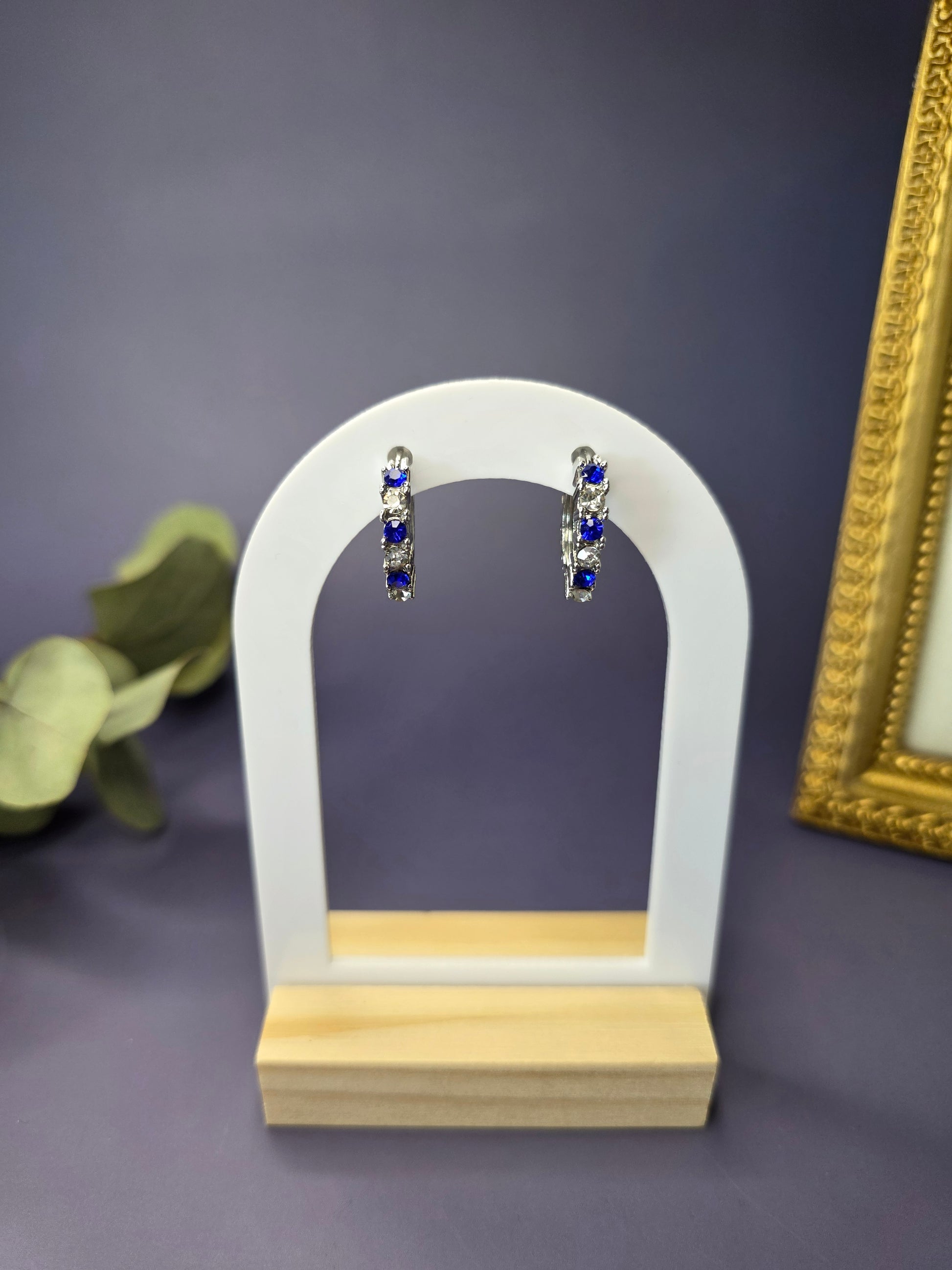 Midnight Starlight huggie hoops featured on a white arch jewelry stand. These S925 sterling silver hypoallergenic hoops provide a celestial blue and white stone pattern - My Silver Lining.