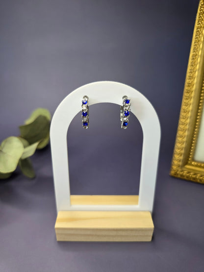 Midnight Starlight huggie hoops featured on a white arch jewelry stand. These S925 sterling silver hypoallergenic hoops provide a celestial blue and white stone pattern - My Silver Lining.