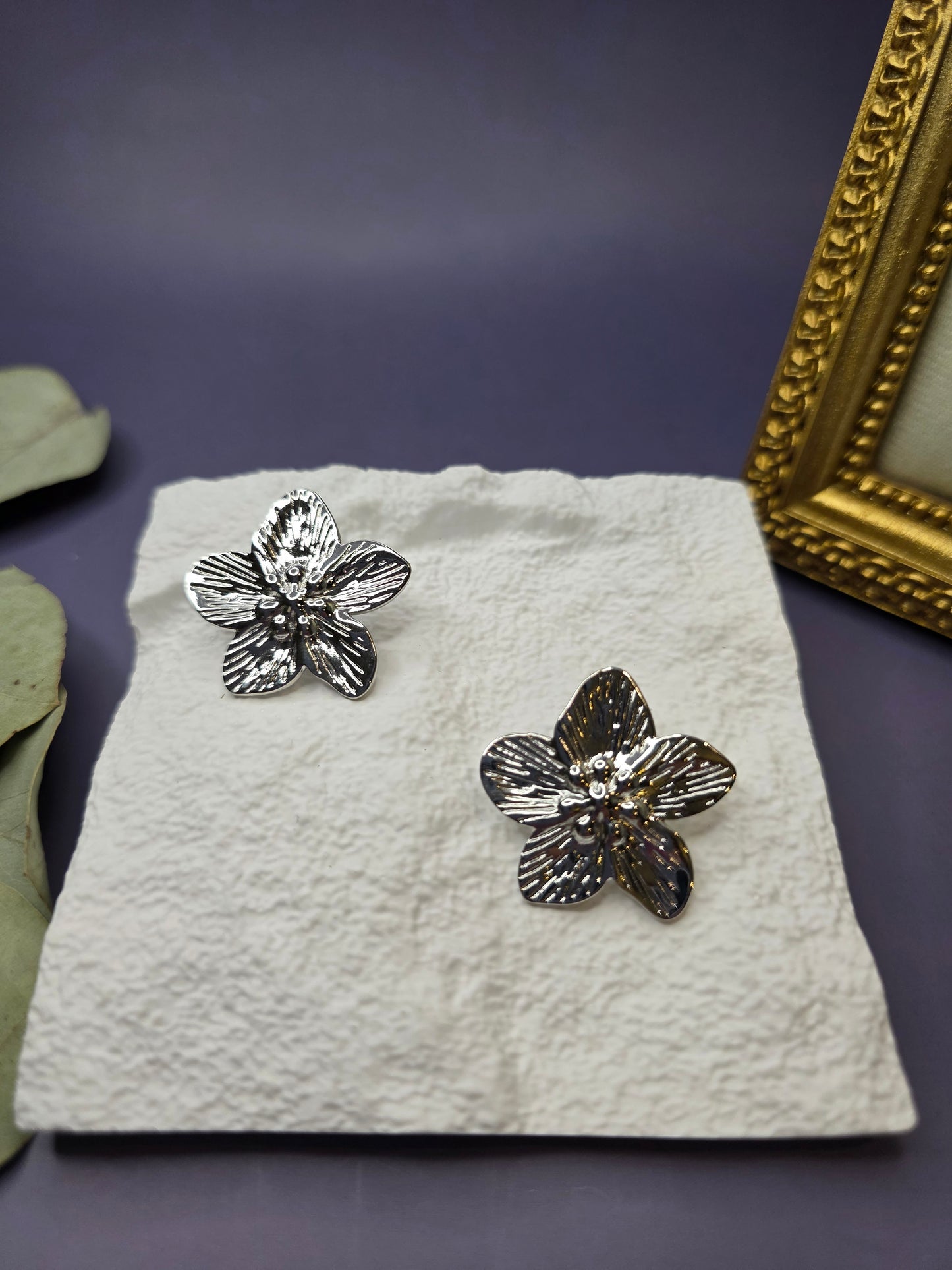 Front view of Moonlight Blossom silver flower stud earrings on a white display stand. These tarnish-resistant stainless steel earrings feature a sunburst texture, perfect for sensitive skin - My Silver Lining.