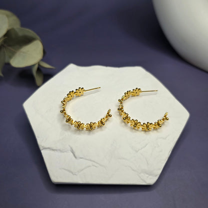 SEO optimized top-down view of My Daisy Hoop Earrings on a white stone, highlighting the intricate floral stainless steel pattern — My Silver Lining.