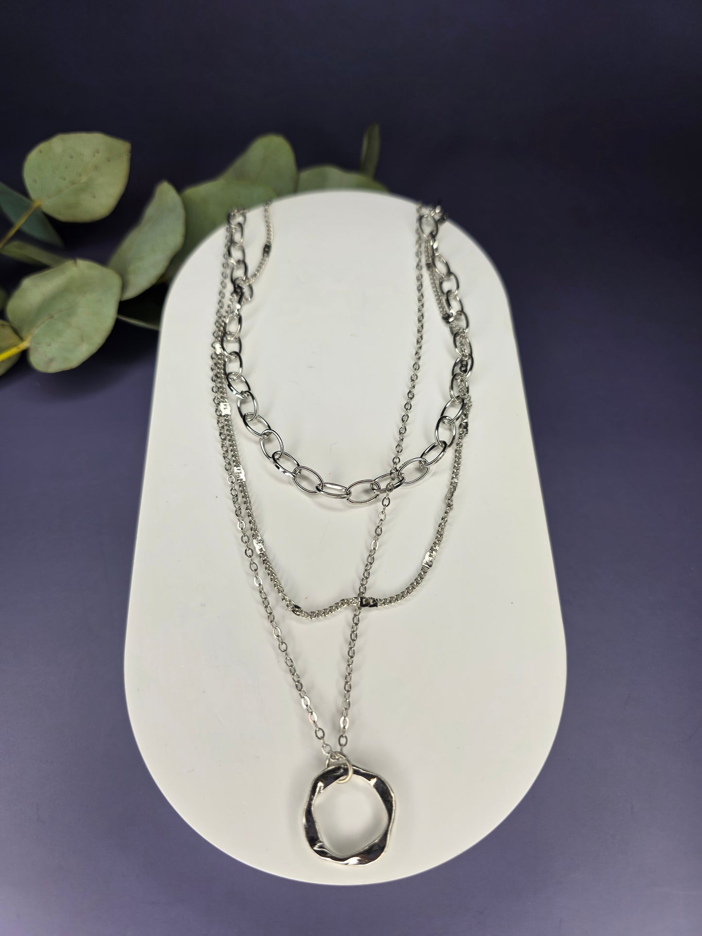 The Silver Line Loop necklace, a single-piece, three-layer necklace set in 925 silver-plated copper. The layers include a chunky oval link chain, a fine chain, and a twisted ring pendant.