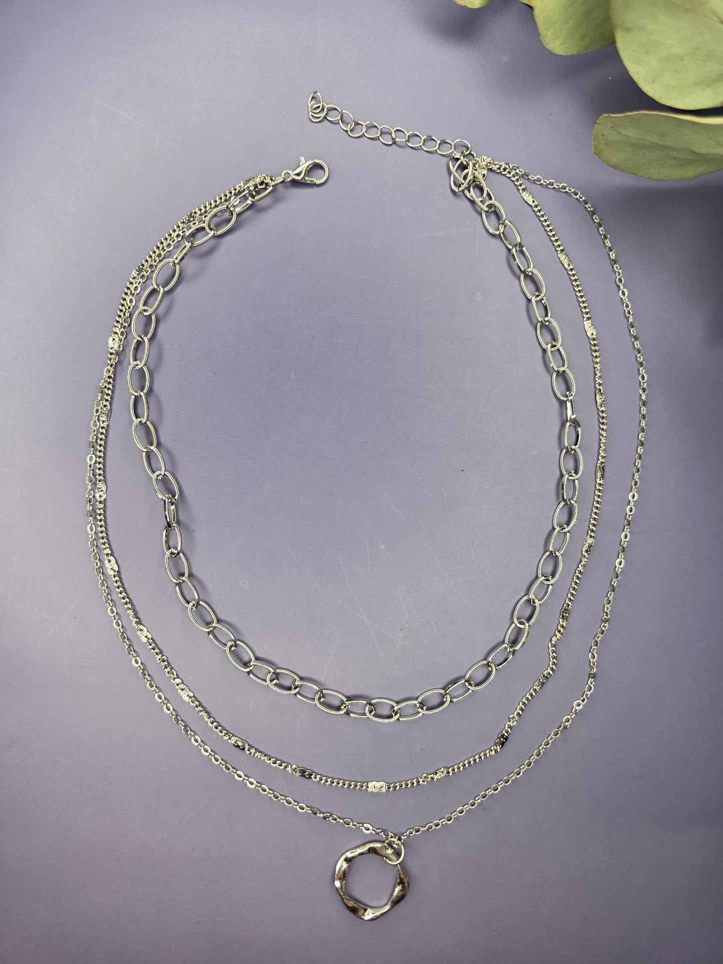 The Silver Line Loop necklace, a single-piece, three-layer necklace set in 925 silver-plated copper. The layers include a chunky oval link chain, a fine chain, and a twisted ring pendant.
