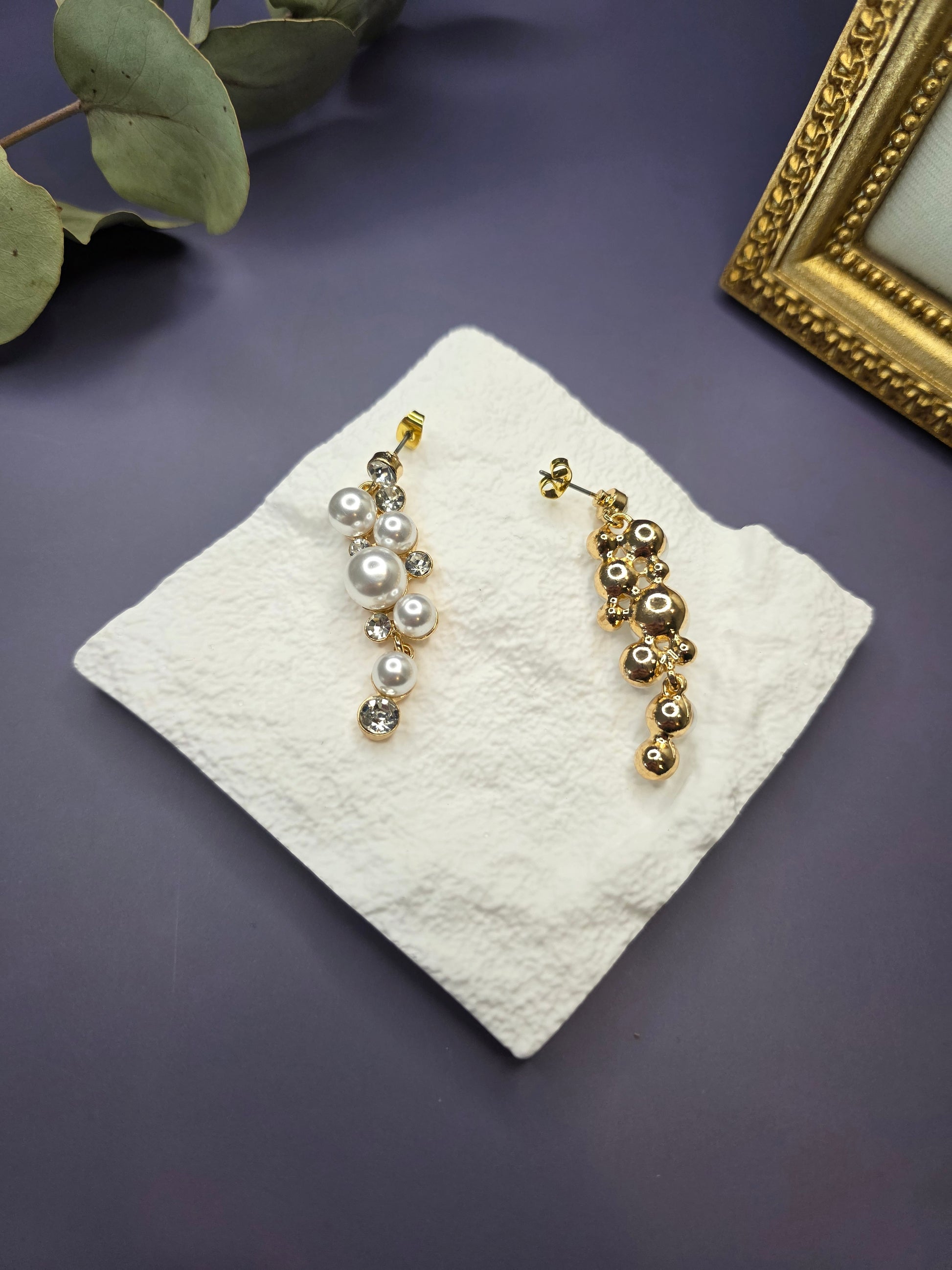 Pearl Cluster Drops displayed (front & back)on a white textured hexagon stone. These 5cm 14K gold plated bridal statement earrings feature imitation pearls, rhinestones, and stainless steel needles - My Silver Lining.