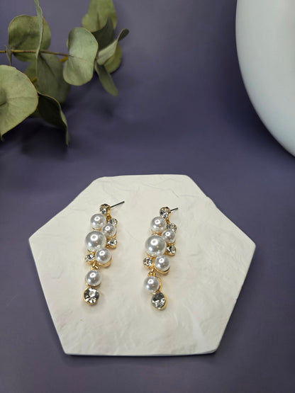 Pearl Cluster Drops displayed on a white textured hexagon stone. These 5cm 14K gold plated bridal statement earrings feature imitation pearls, rhinestones, and stainless steel needles - My Silver Lining.