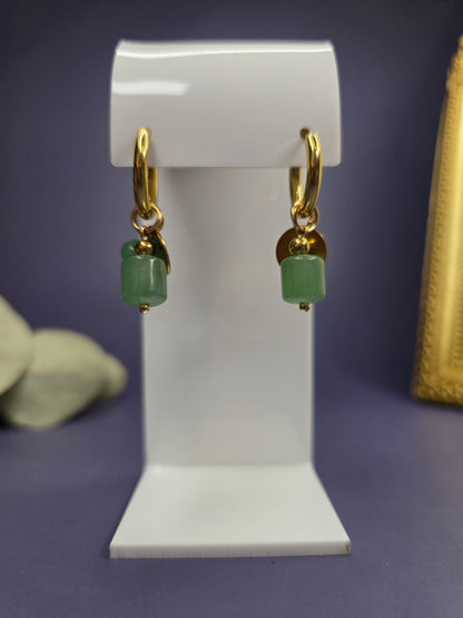 Front-facing view of the Rustic Olive Huggies on a white display stand. 18k gold plated huggies with green stone and gold disc charms — My Silver Lining.