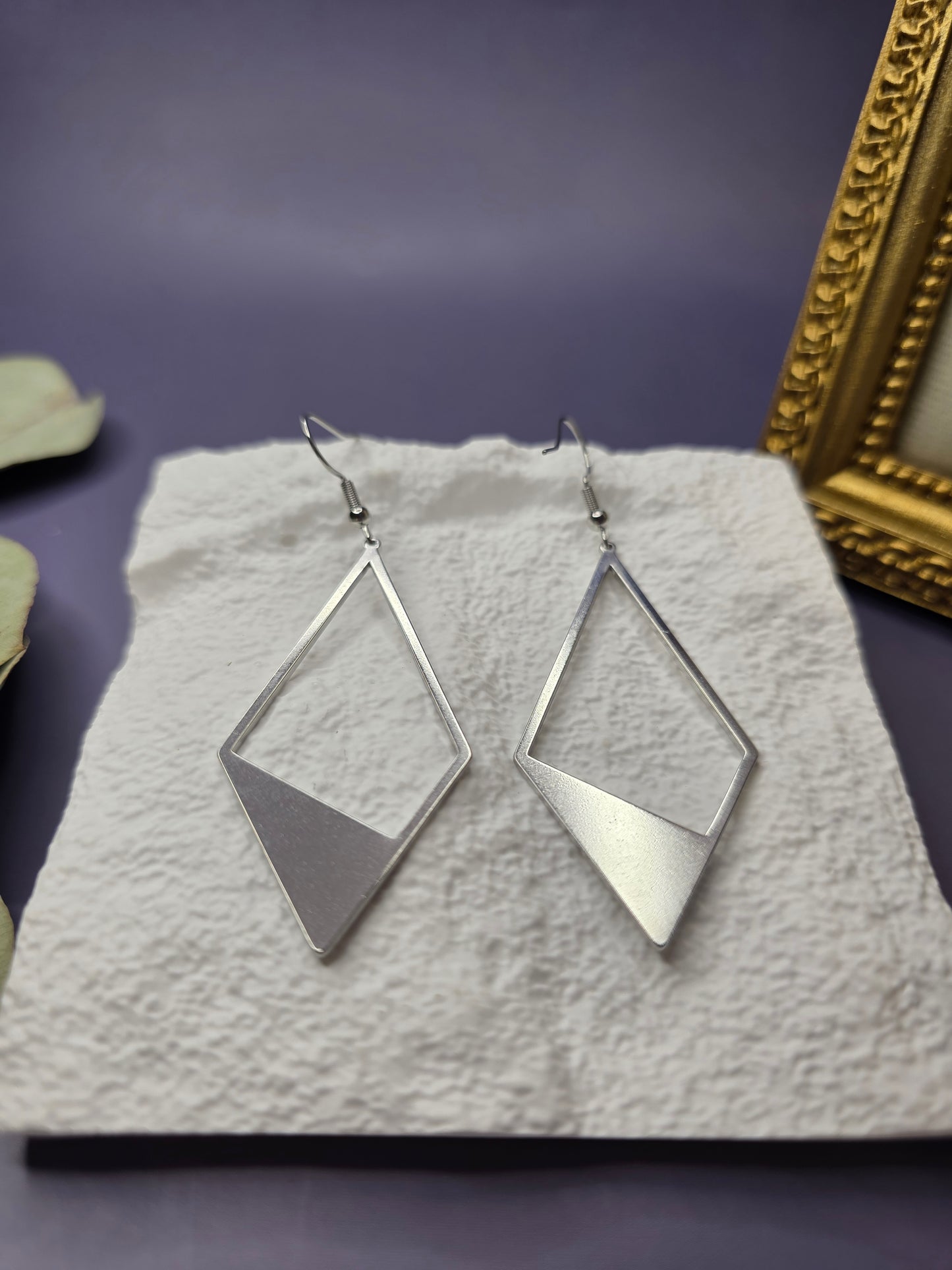 Detail shot of Silver Anchor Drops resting on a white textured stone. High-quality waterproof and tarnish-resistant silver earrings with hypoallergenic medical-grade needles for sensitive ears - My Silver Lining.