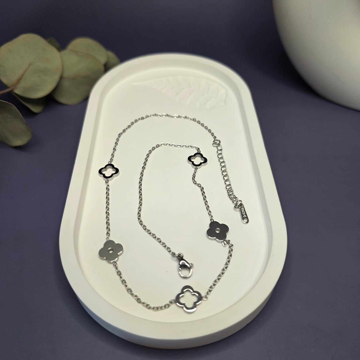 Close-up of the silver four-leaf clover charm on a white tray, highlighting the high-polish 316 stainless steel — My Silver Lining.