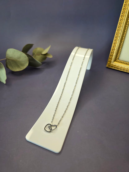 Silver Dual Hearts necklace featuring interlocking heart charms on a white curved display. This 316 stainless steel pendant is hypoallergenic and designed for enduring brilliance - My Silver Lining.