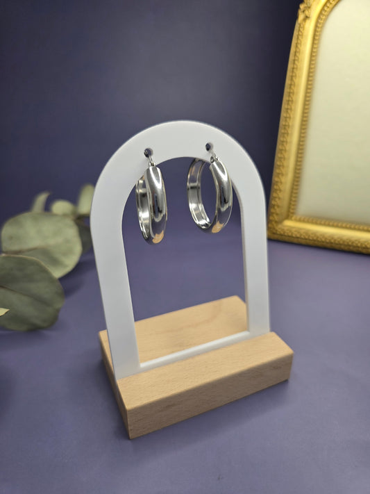 Silver halo hoops featured on a white arch jewelry stand. These 304 stainless steel waterproof earrings provide a sleek, minimalist silhouette and a hypoallergenic finish for every day wear - My Silver Lining.