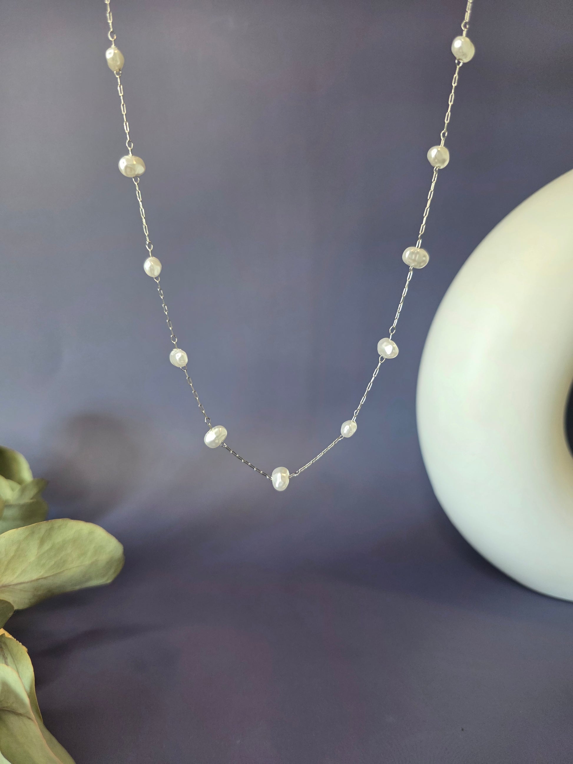 Silver station necklace with pearls arranged in a nature-inspired lifestyle setting. This durable, waterproof stainless steel necklace offers a timeless French aesthetic, perfect for effortless styling and individuality - My Silver Lining.