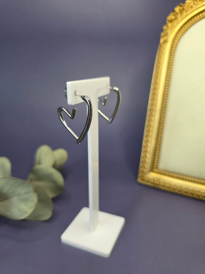 Silver open heart earrings featured on a white T-stand display. These 3x3 cm waterproof 316 stainless steel heart hoops offer a modern, minimalist silhouette for everyday elegance - My Silver Lining