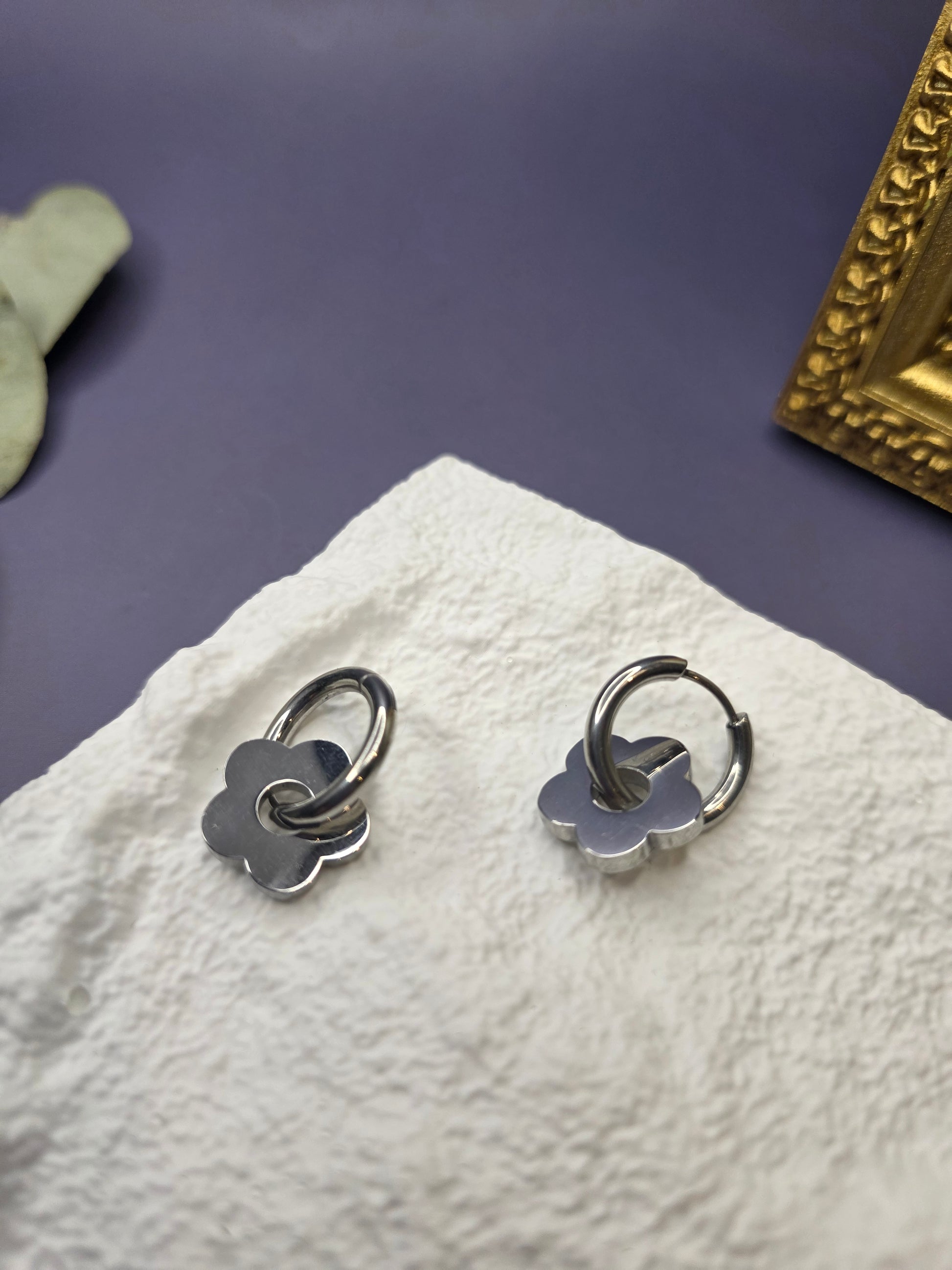 Silver Retro Bloom hoops displayed on a white textured hexagon stone. These 2.3cm waterproof 316 stainless steel earrings feature dangling flower charms - My Silver Lining.