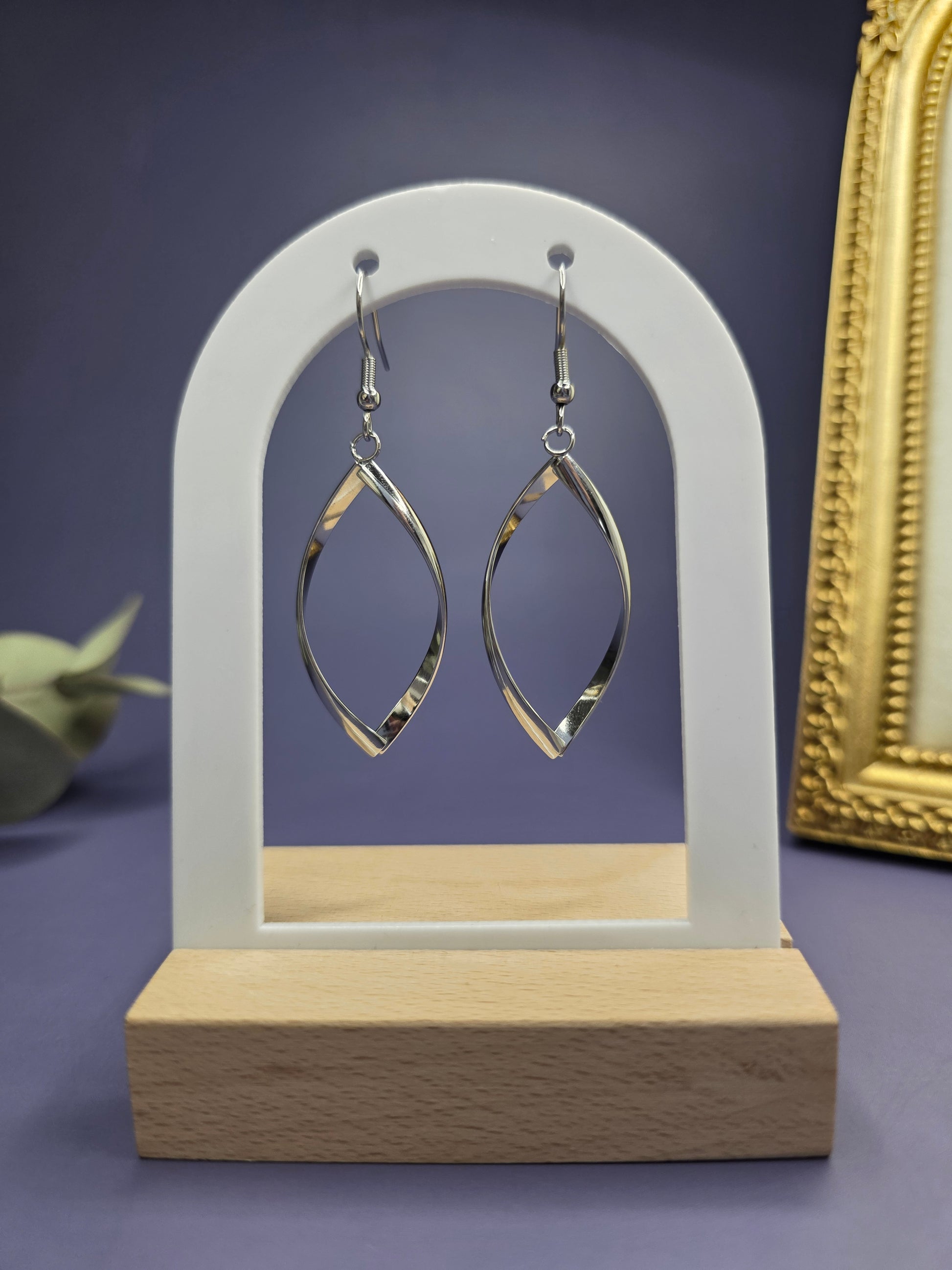Silver ribbon earrings featured on a white arch jewelry stand. These 316 stainless steel waterproof earrings provide a striking 7cm elongated silhouette and a hypoallergenic finish for sophisticated wear - My Silver Lining.