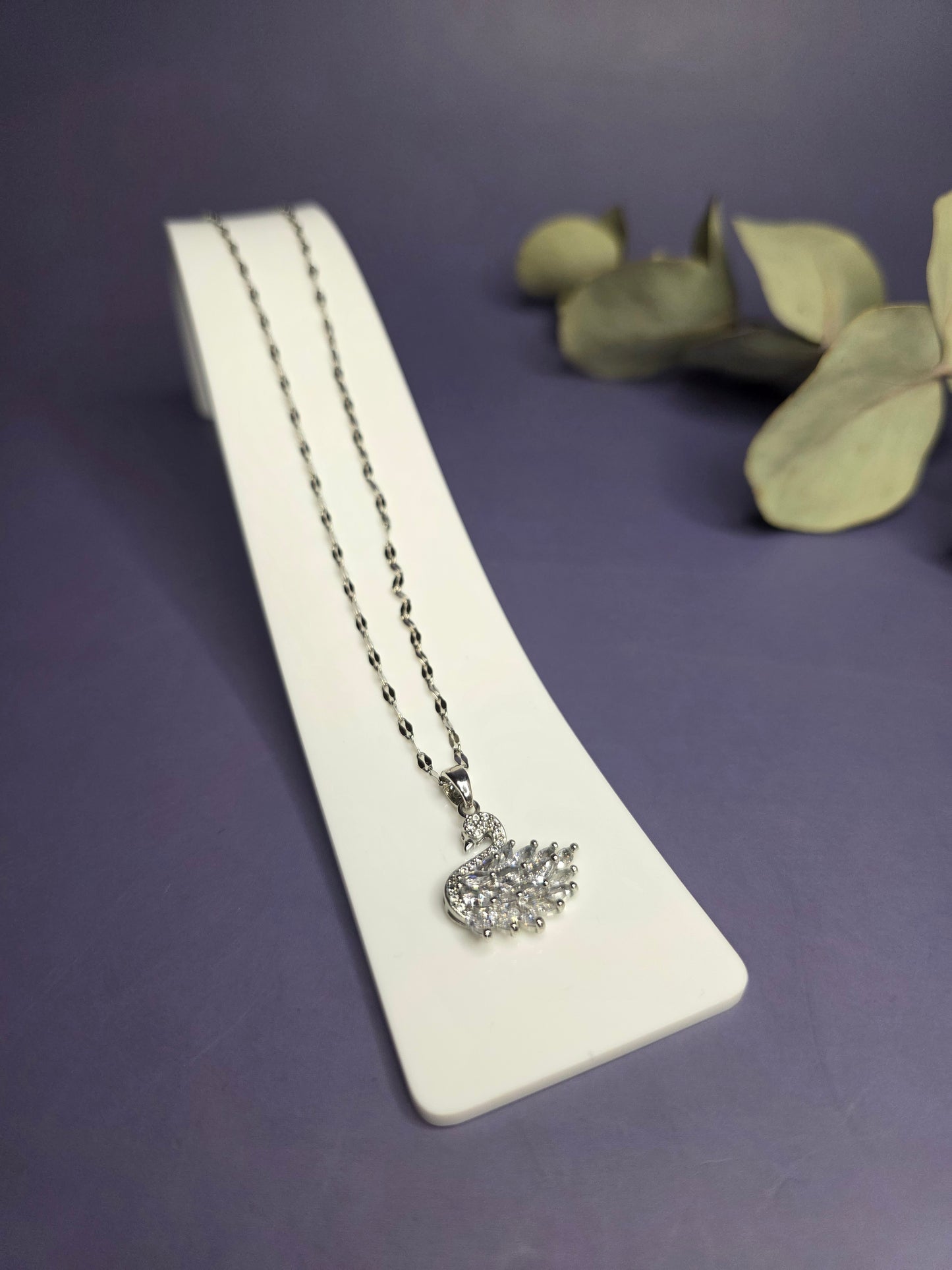 Angled view of the Silver White Swan Lake Necklace in polished stainless steel on a white display stand — My Silver Lining.