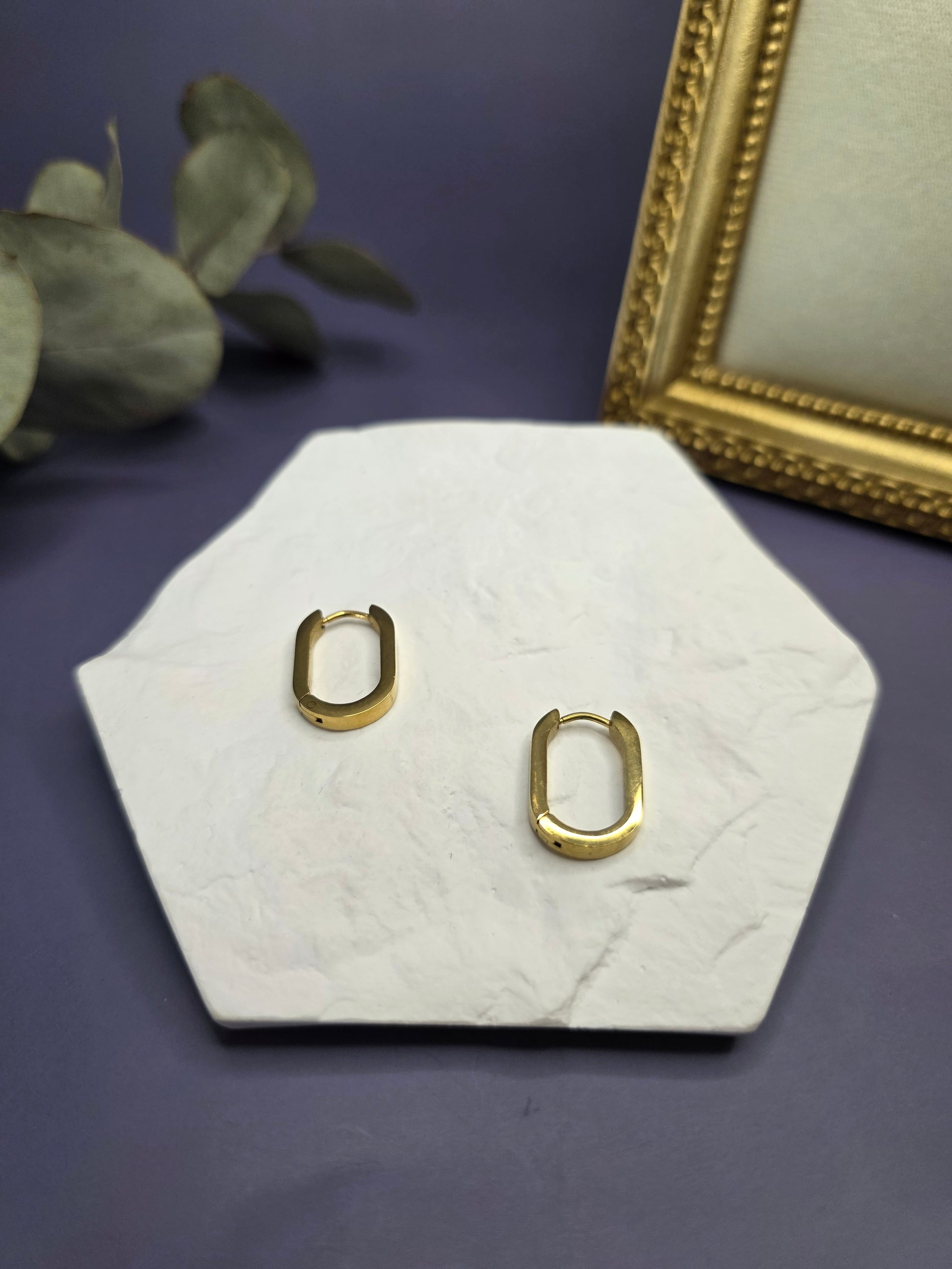 Soft Square golden hoops displayed on a white textured hexagon stone. These 316 stainless steel KC gold plated sleepers are waterproof, tarnish-resistant, and hypoallergenic for daily wear — My Silver Lining.