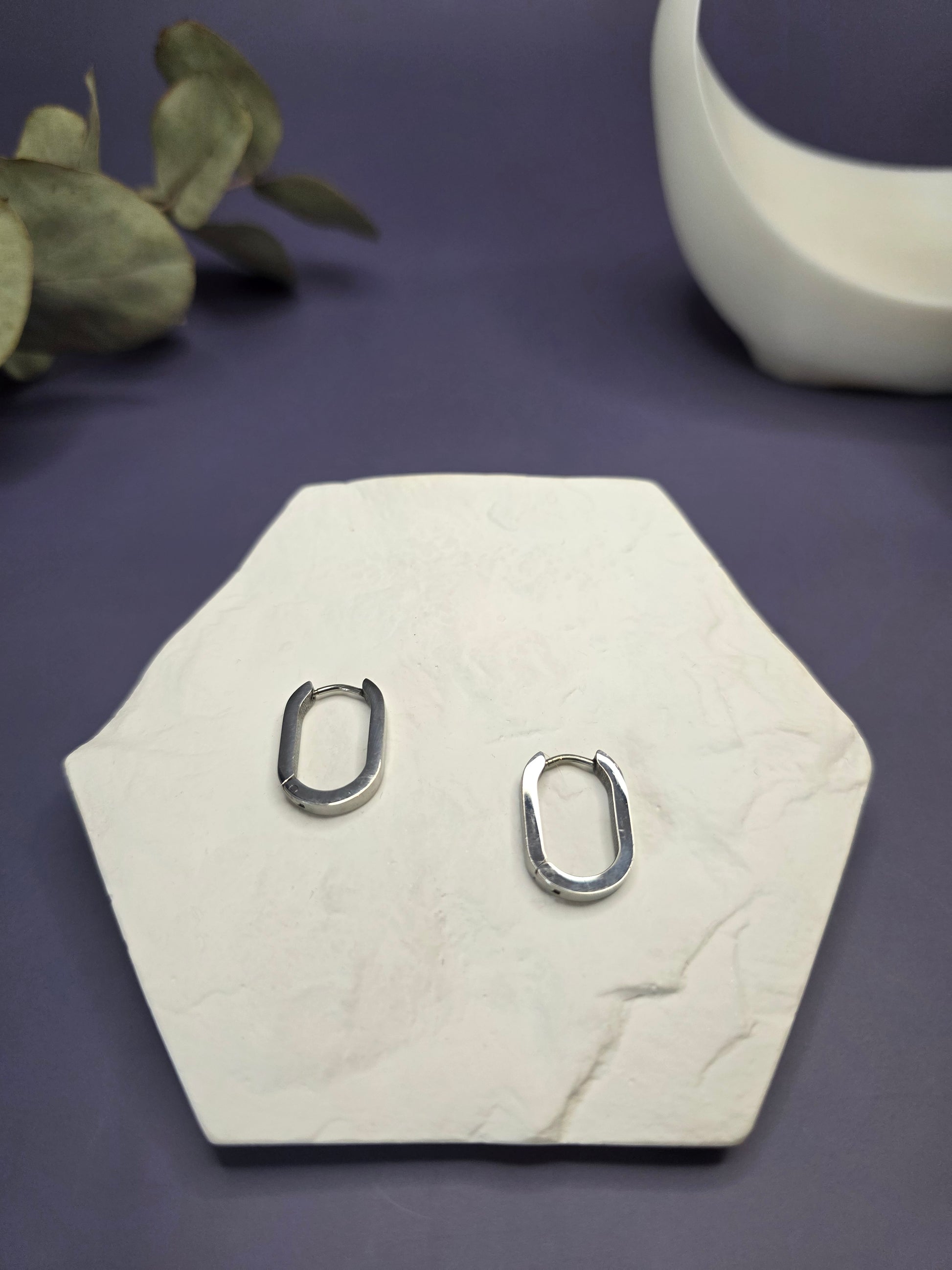 Soft Square silver hoops displayed on a white textured hexagon stone. These 316 stainless steel earrings are waterproof, tarnish-resistant, and hypoallergenic for everyday wear. Perfect sleepers — My Silver Lining.