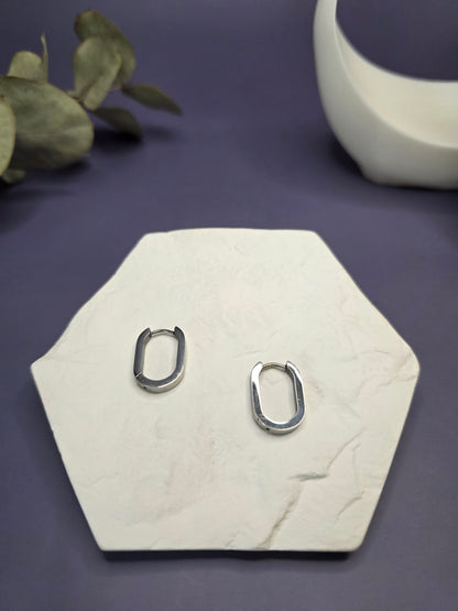 Soft Square silver hoops displayed on a white textured hexagon stone. These 316 stainless steel earrings are waterproof, tarnish-resistant, and hypoallergenic for everyday wear. Perfect sleepers — My Silver Lining.