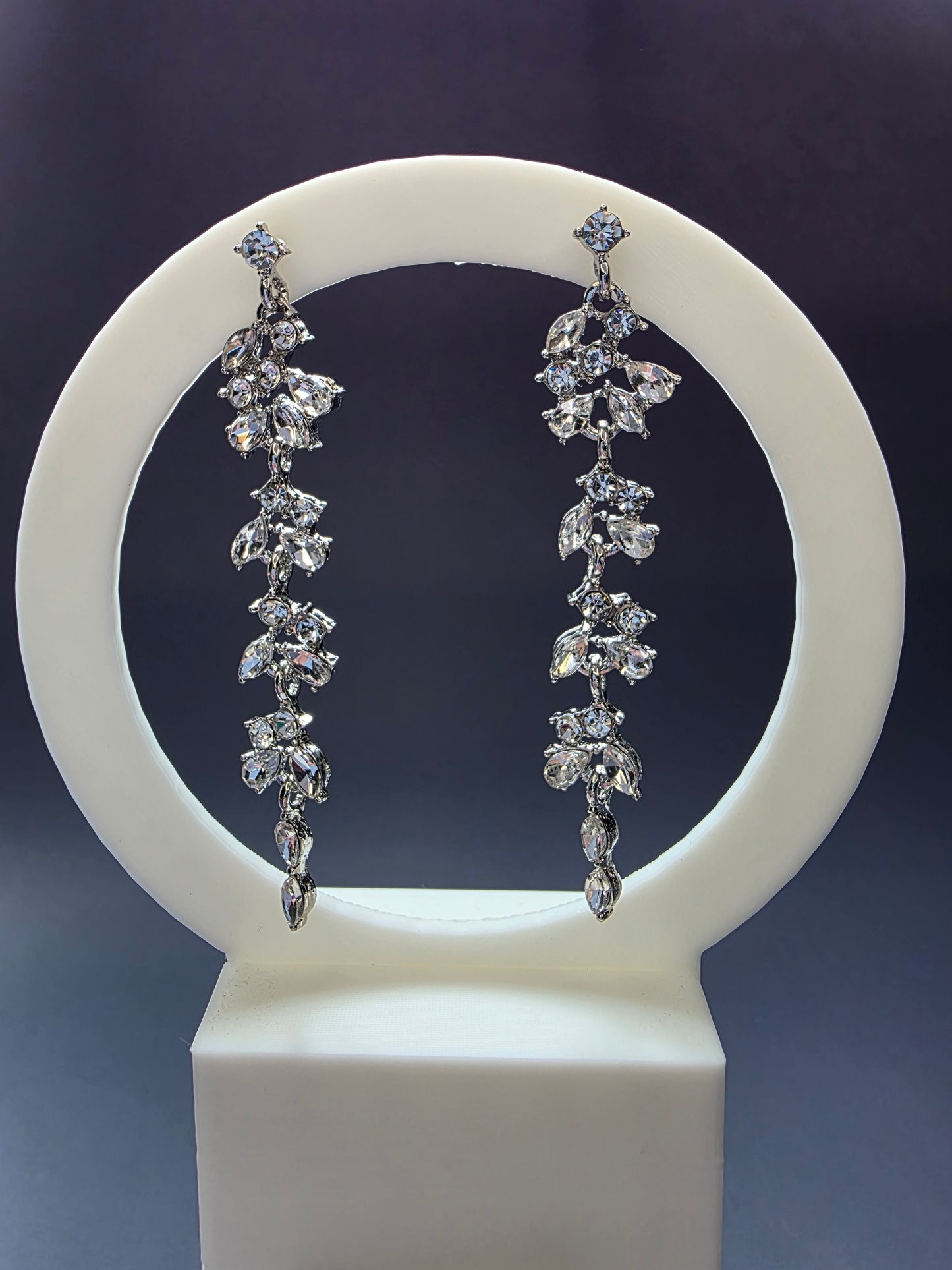 Starlight Vine Drops featured on a white arch jewelry stand. These 8cm long clear zircon chandelier earrings provide a dramatic silhouette and hypoallergenic S925 silver finish - My Silver Lining.