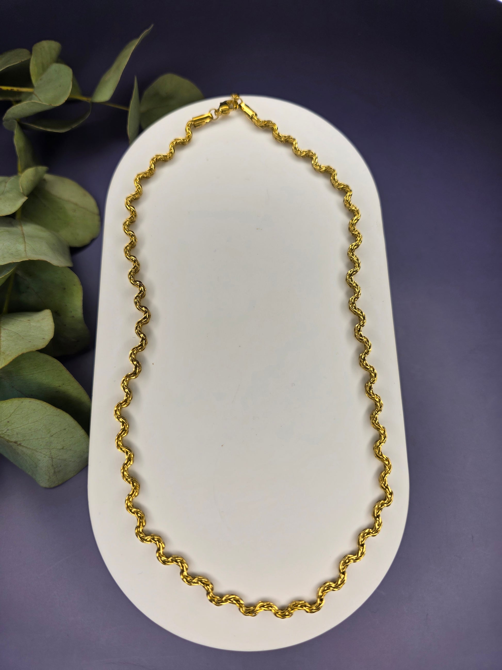 Model view of the gold-plated Dorian Chain necklace, showing how the wavy-link choker rests gracefully on a beige fabric bust. The chain is 41 cm long with a 5 cm extender.