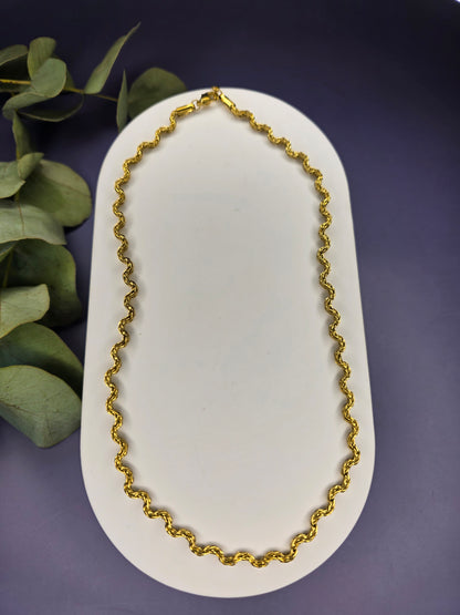 Model view of the gold-plated Dorian Chain necklace, showing how the wavy-link choker rests gracefully on a beige fabric bust. The chain is 41 cm long with a 5 cm extender.