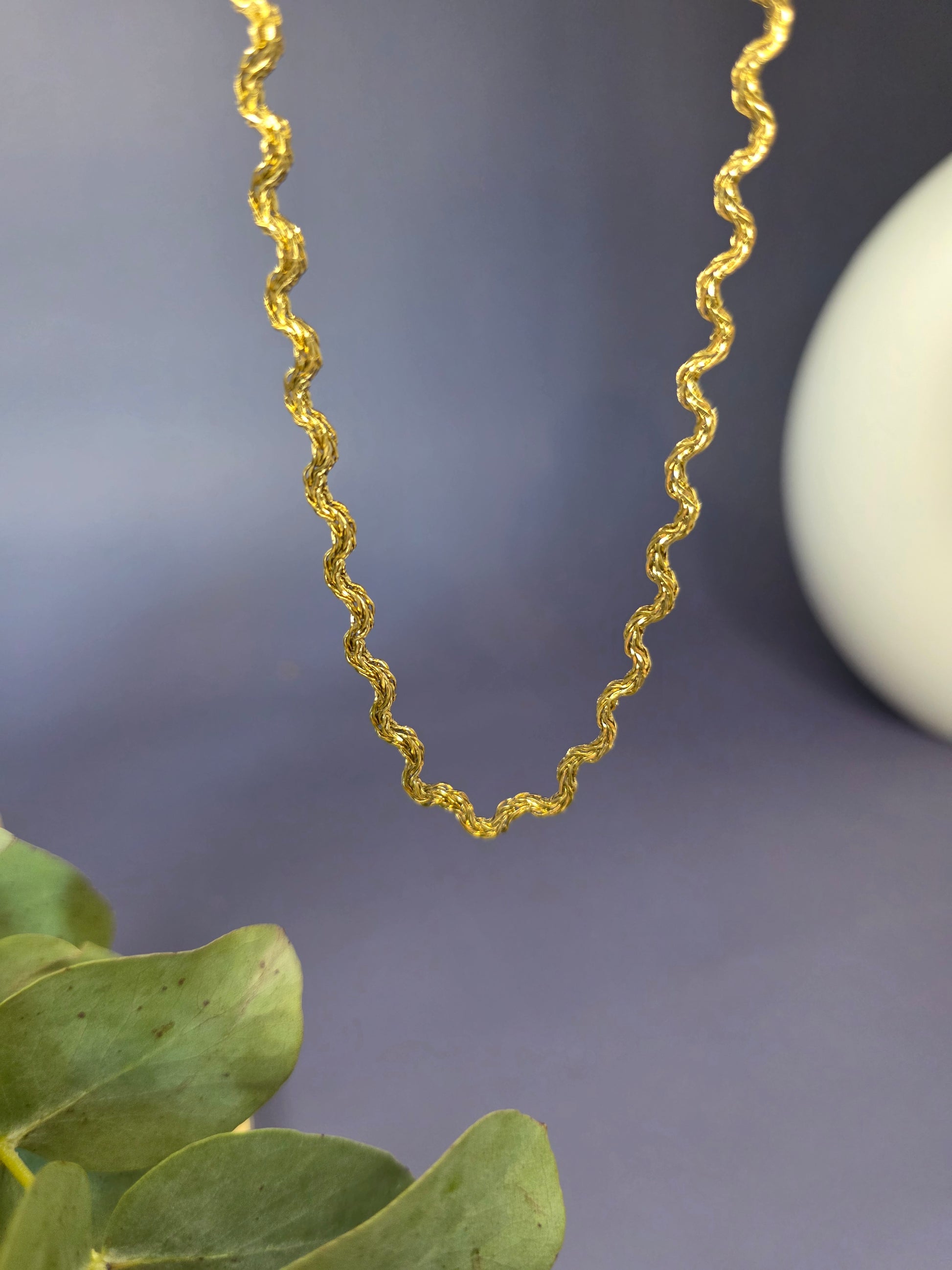 Model view of the gold-plated Dorian Chain necklace, showing how the wavy-link choker rests gracefully on a beige fabric bust. The chain is $41 \text{ cm}$ long with a $5 \text{ cm}$ extender.