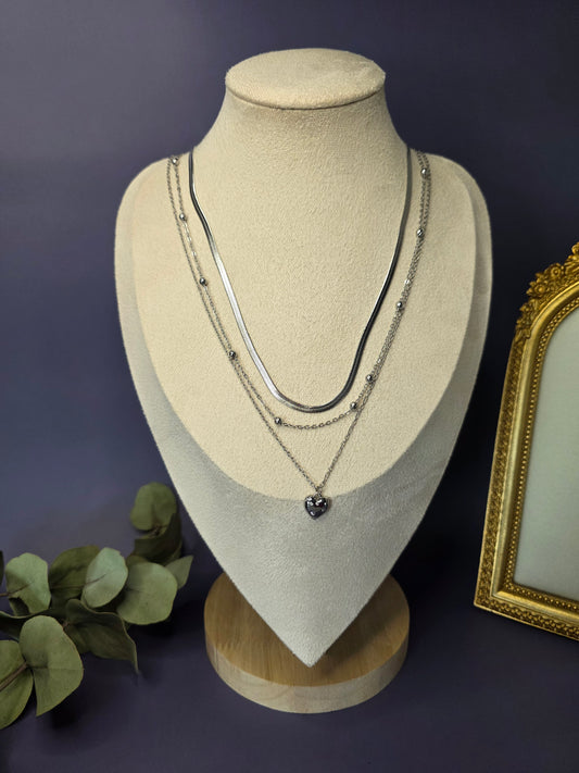 The Siren Serenity silver layered set styled on a white jewelry bust. This 3-piece stainless steel set features a heart pendant and mixed-link chains - My Silver Lining.